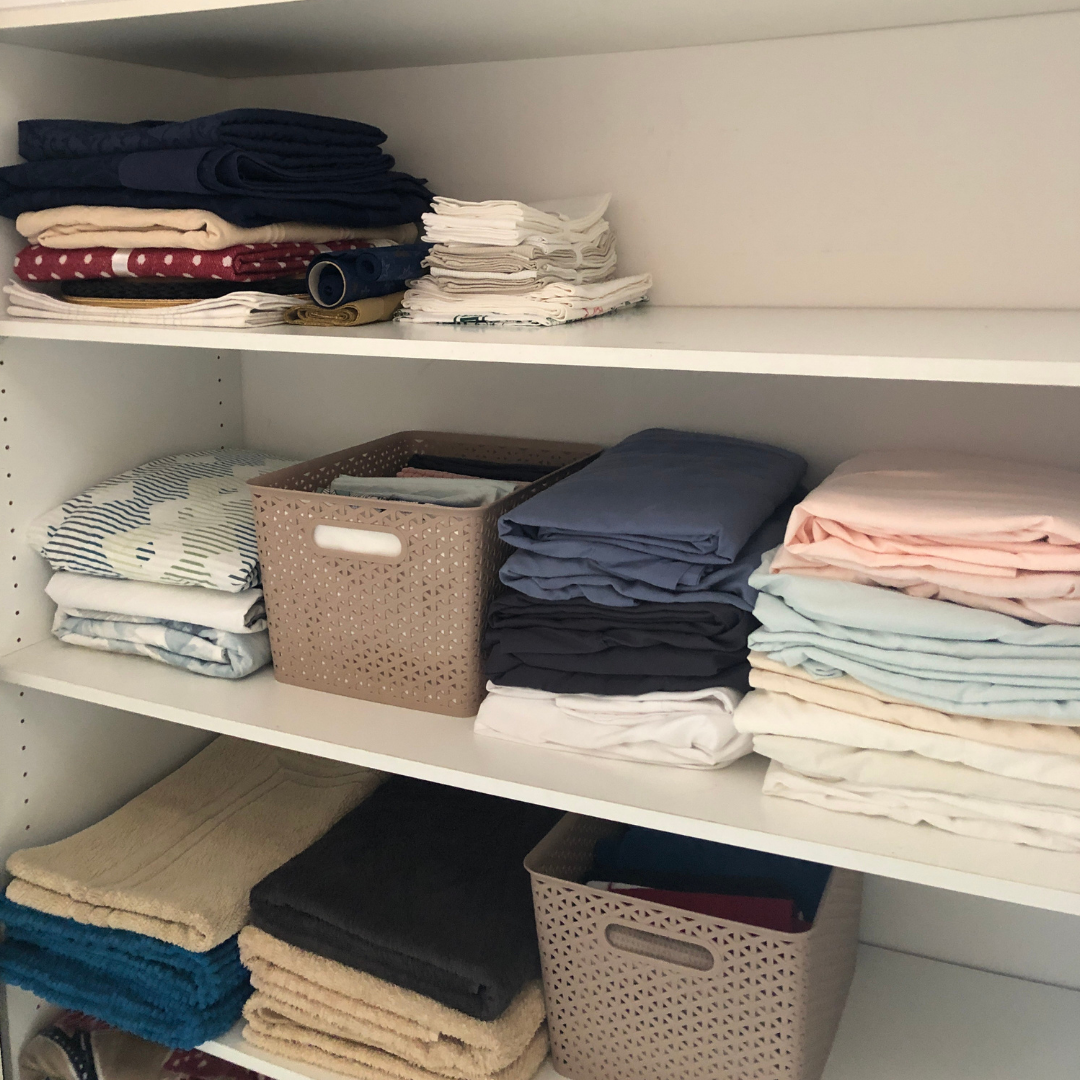 Linen closet with neatly folded fitted sheets on shelf