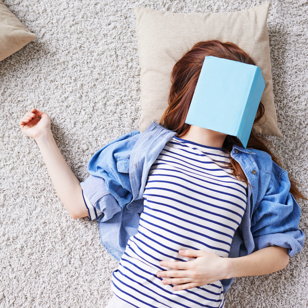 woman lying on pillow with book over her face