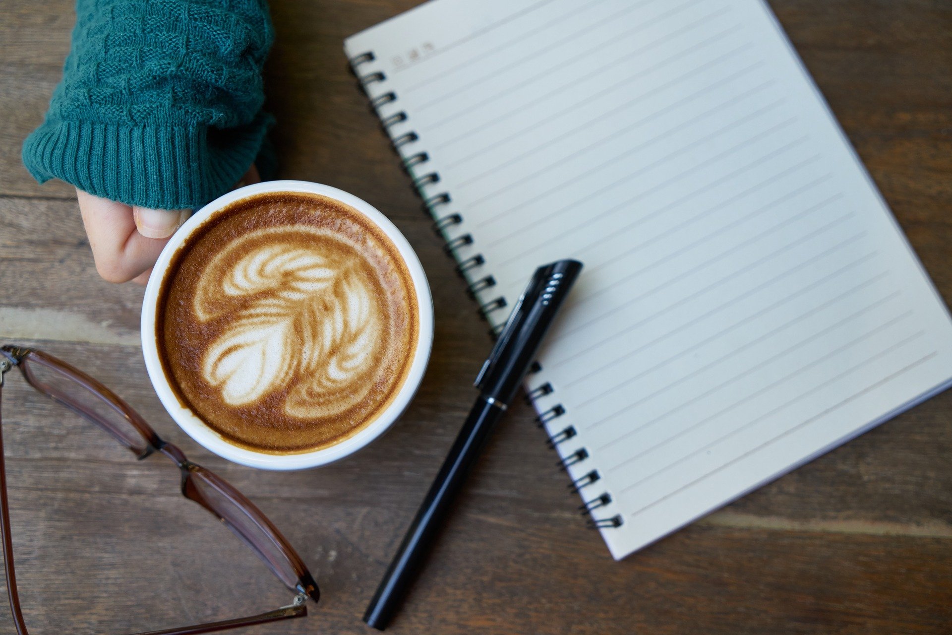 coffee cup, pen, journal, and eyeglasses