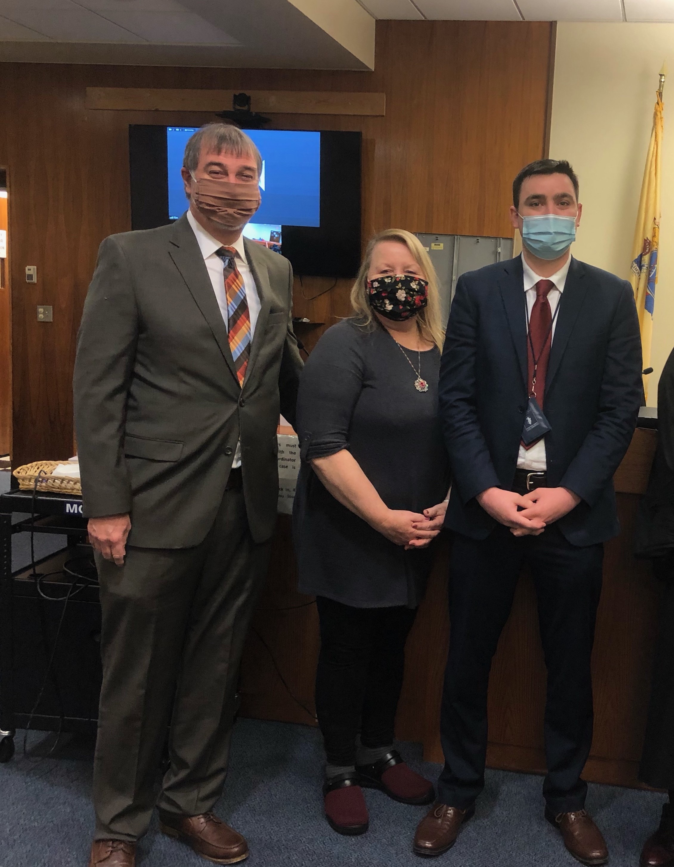 Father, mother, adult son standing together, all wearing masks