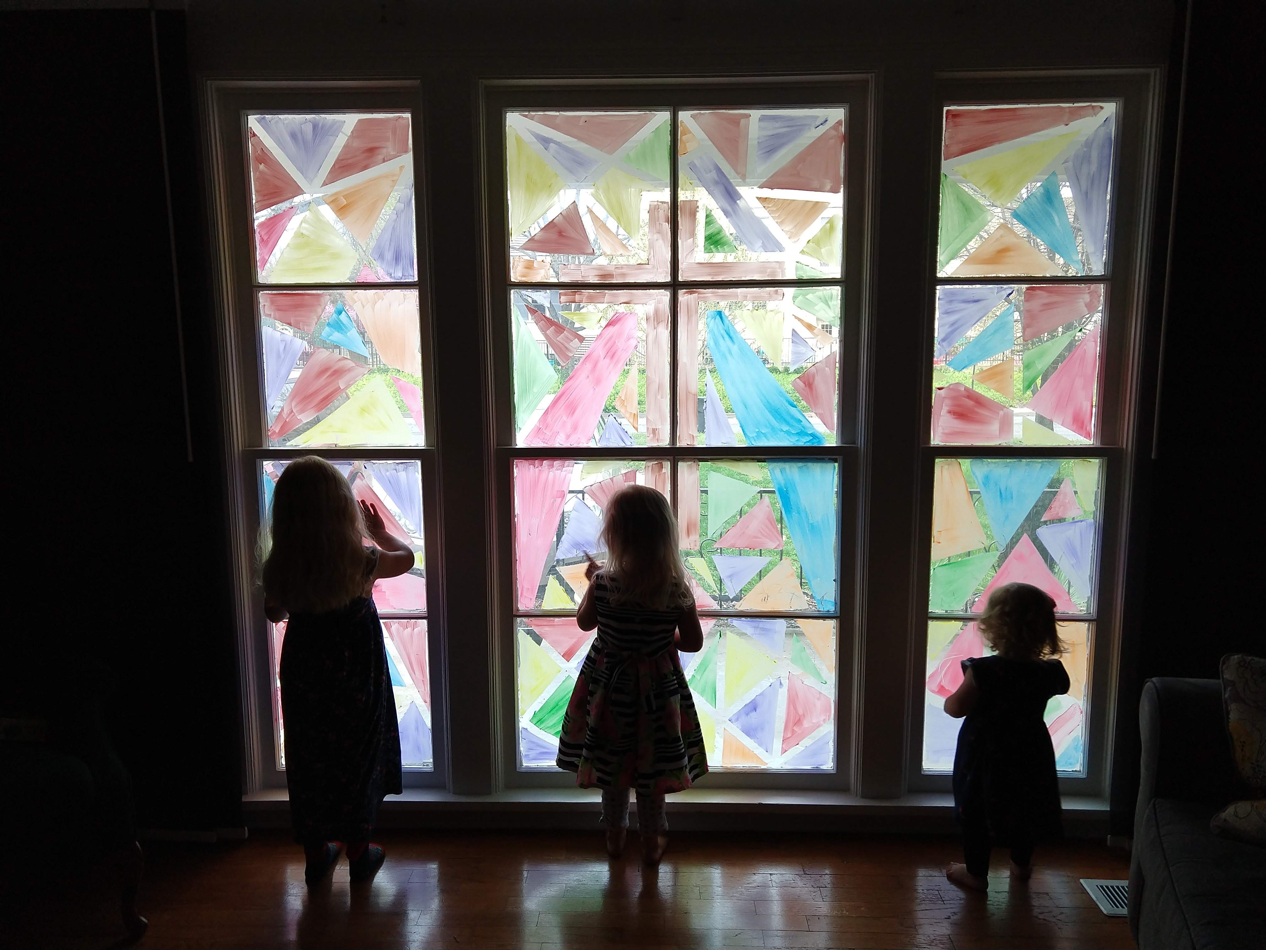 3 little girls silhouetted in front of Easter decorated stained glass window