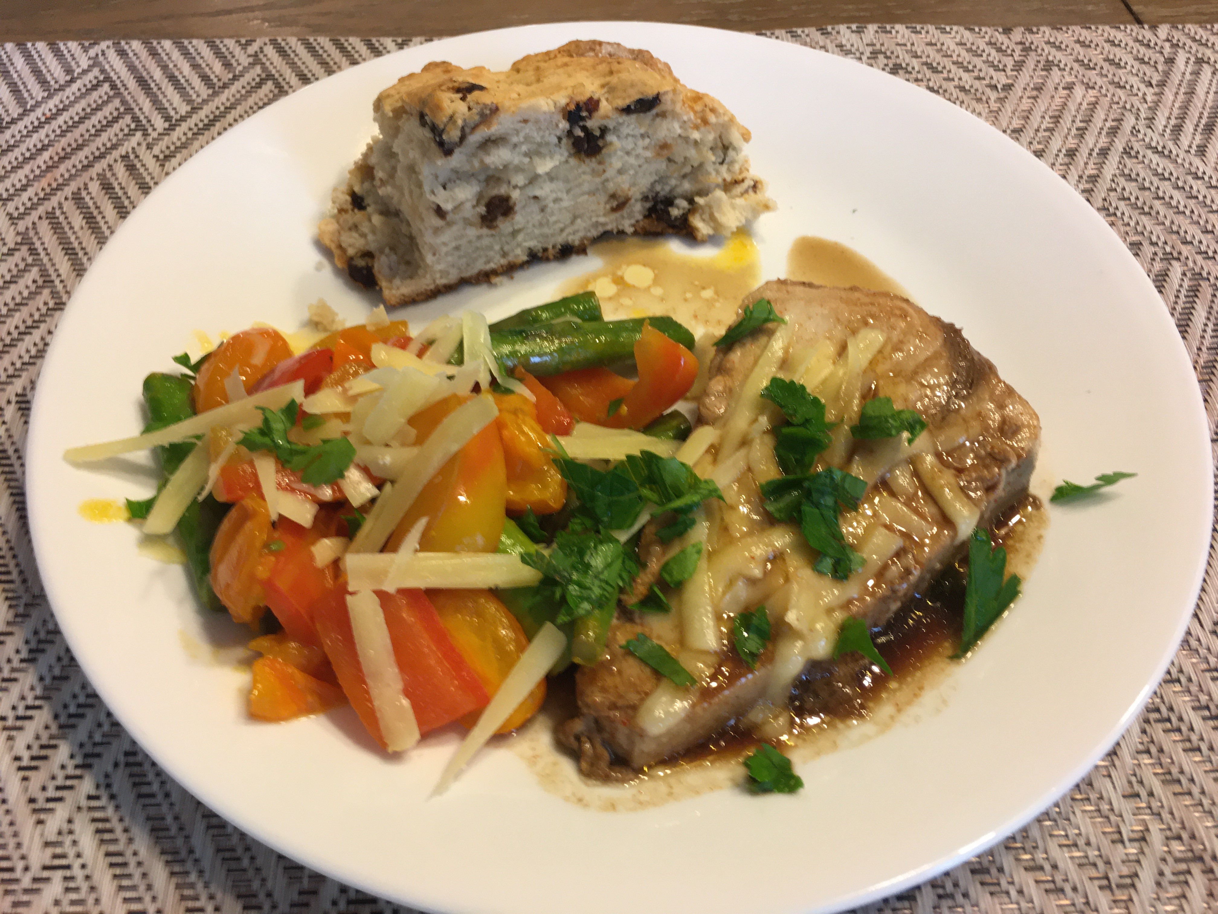 Colorful vegetables with cheese, Irish soda bread, fish with parsley on white plate