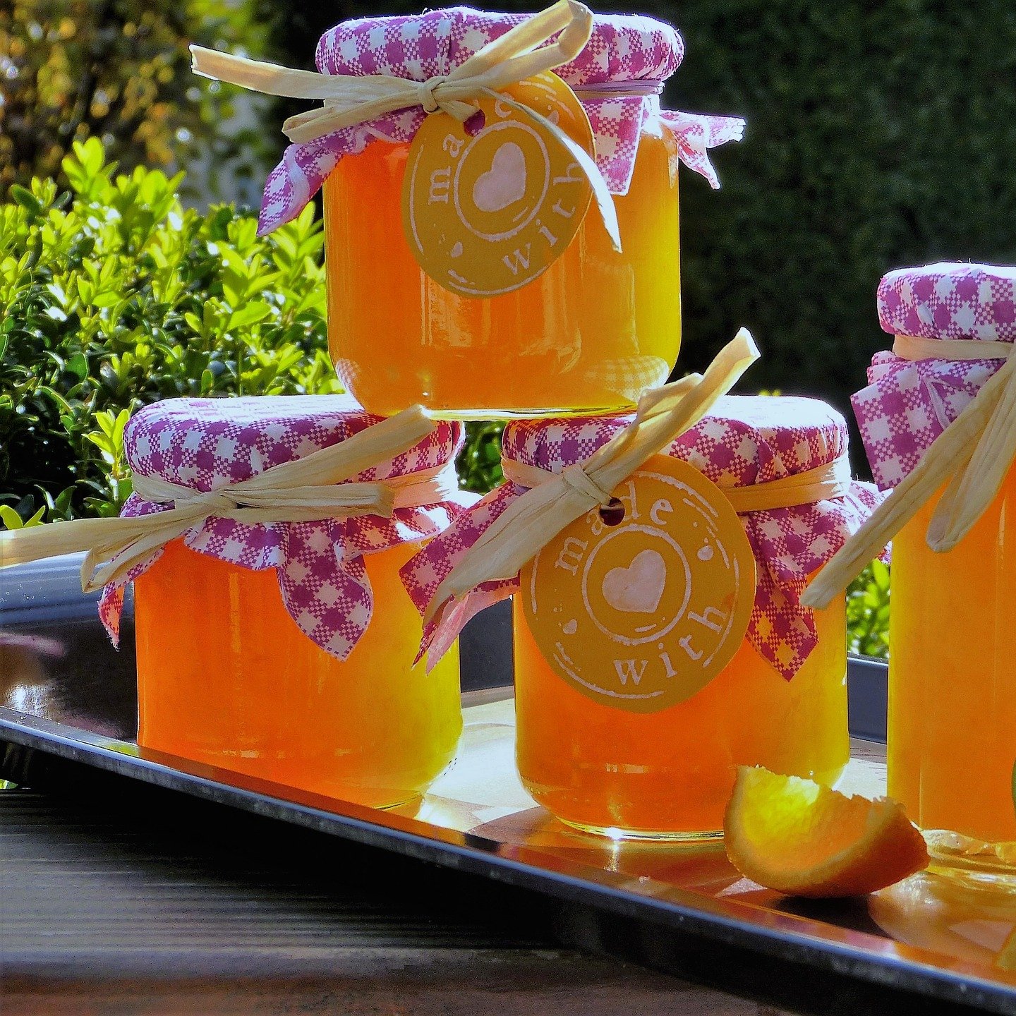 jars of orange marmalade with handcrafted lids and tags on tray with citrus slices