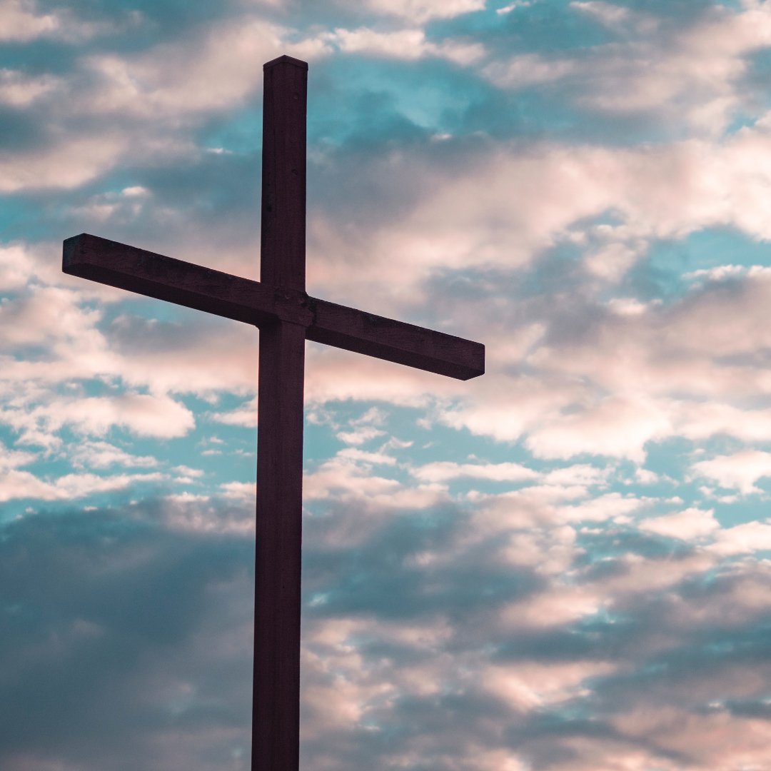 cross silhouette against a blue sky with pink clouds