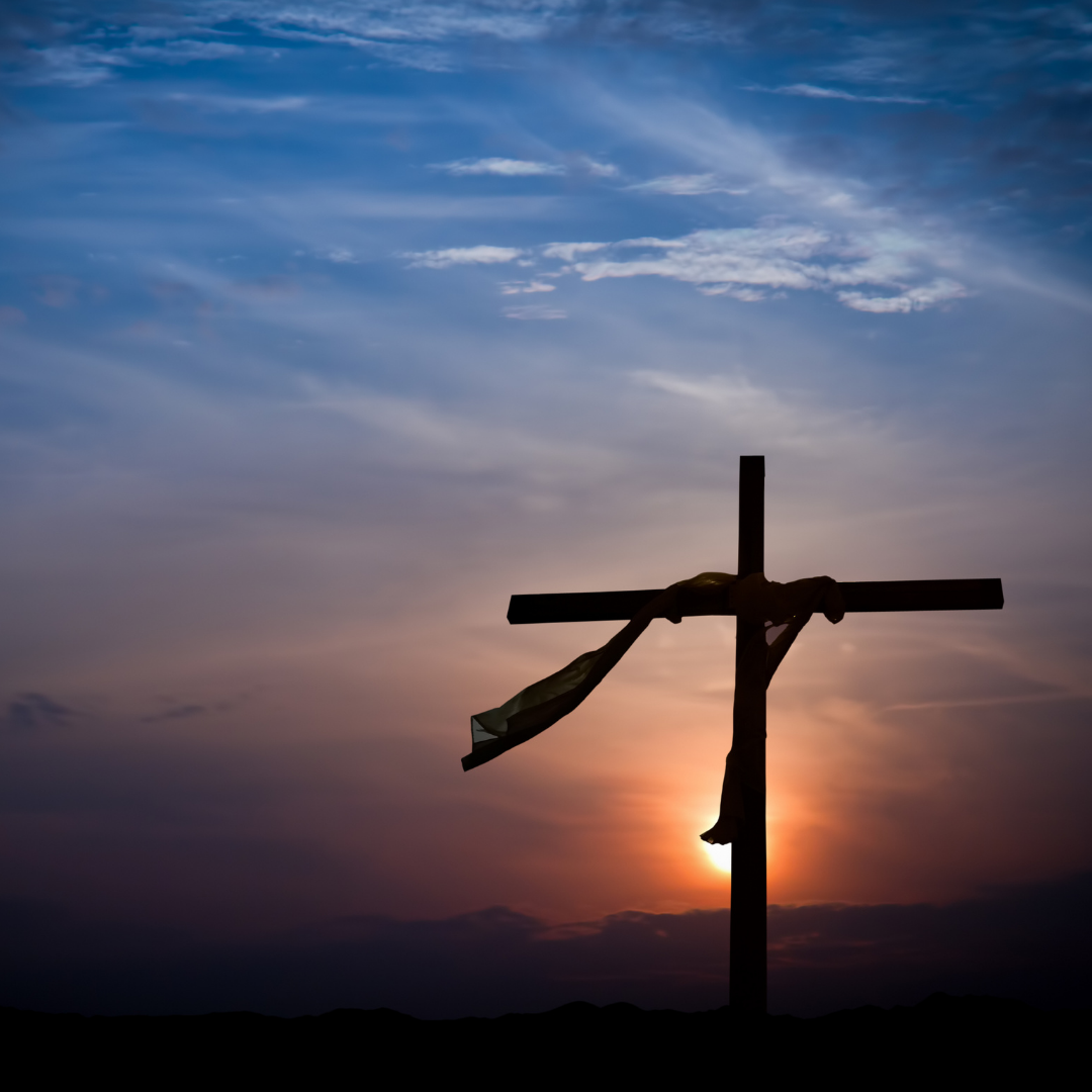 cross with fabric draped over it, sunset in background