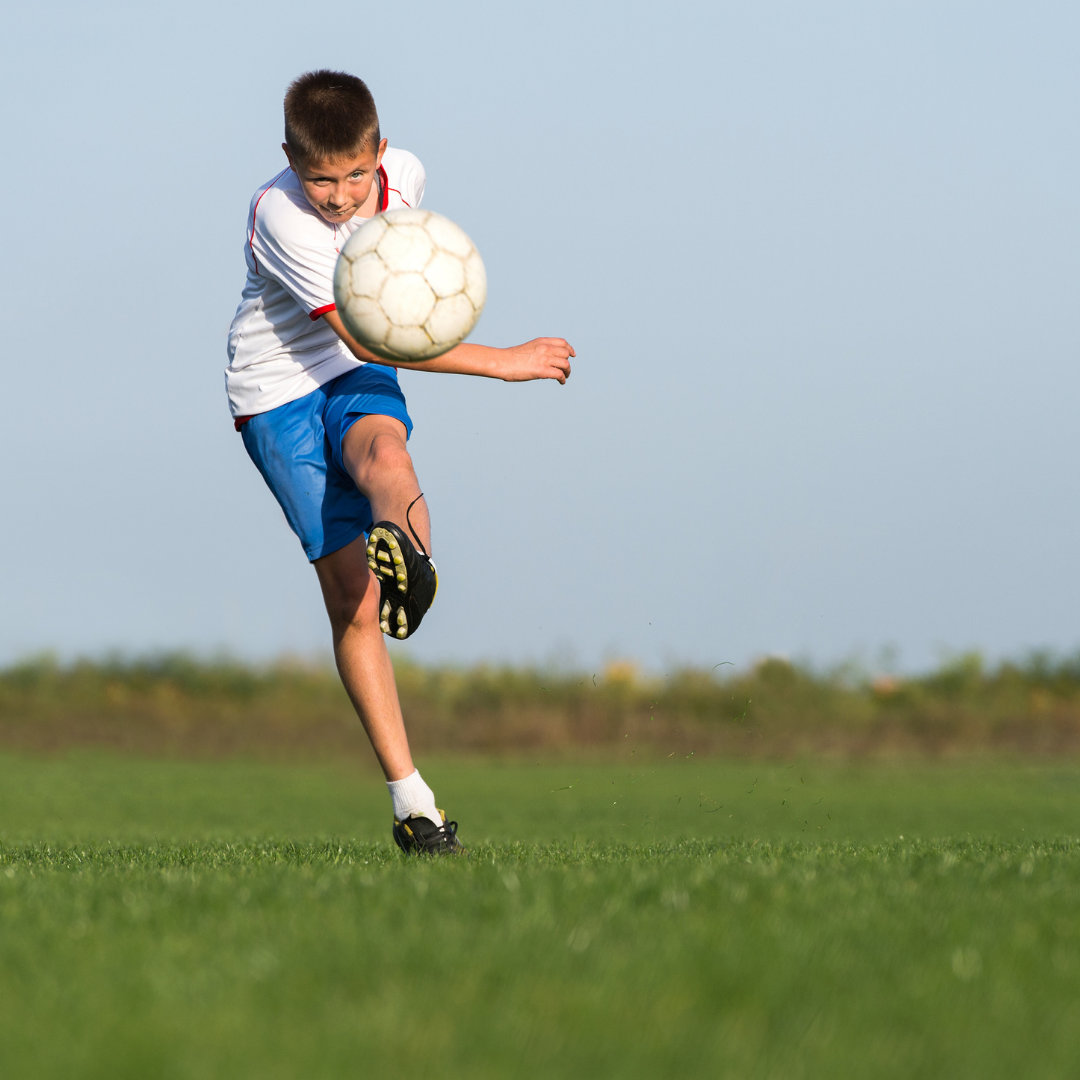 Teenage male kicking soccer ball