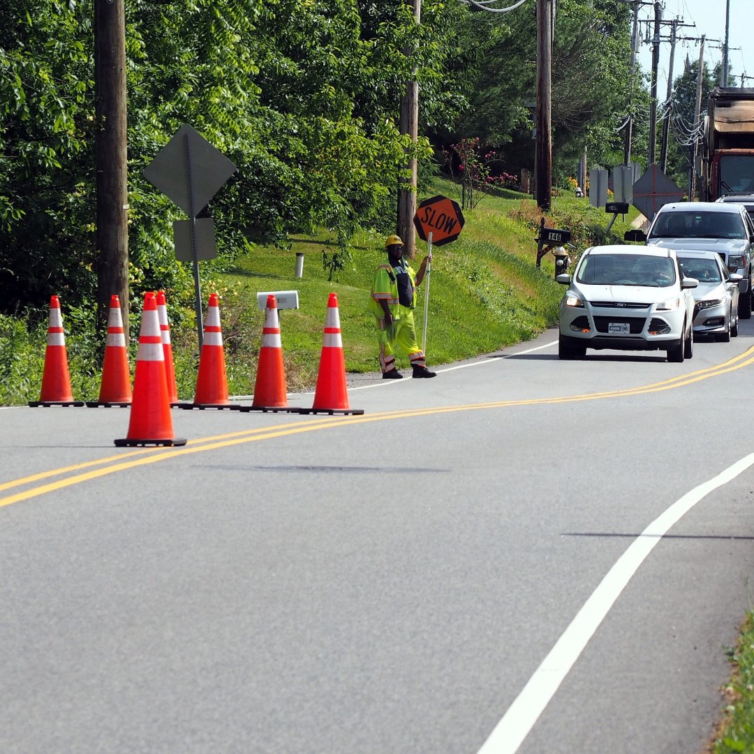 Traffic stopped behind flagman, detour cones in foreground