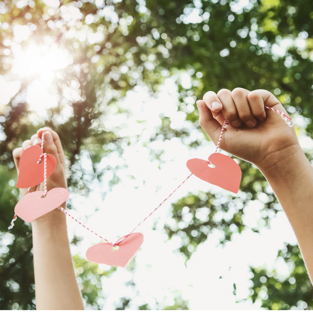 Hands holding a string of paper hearts