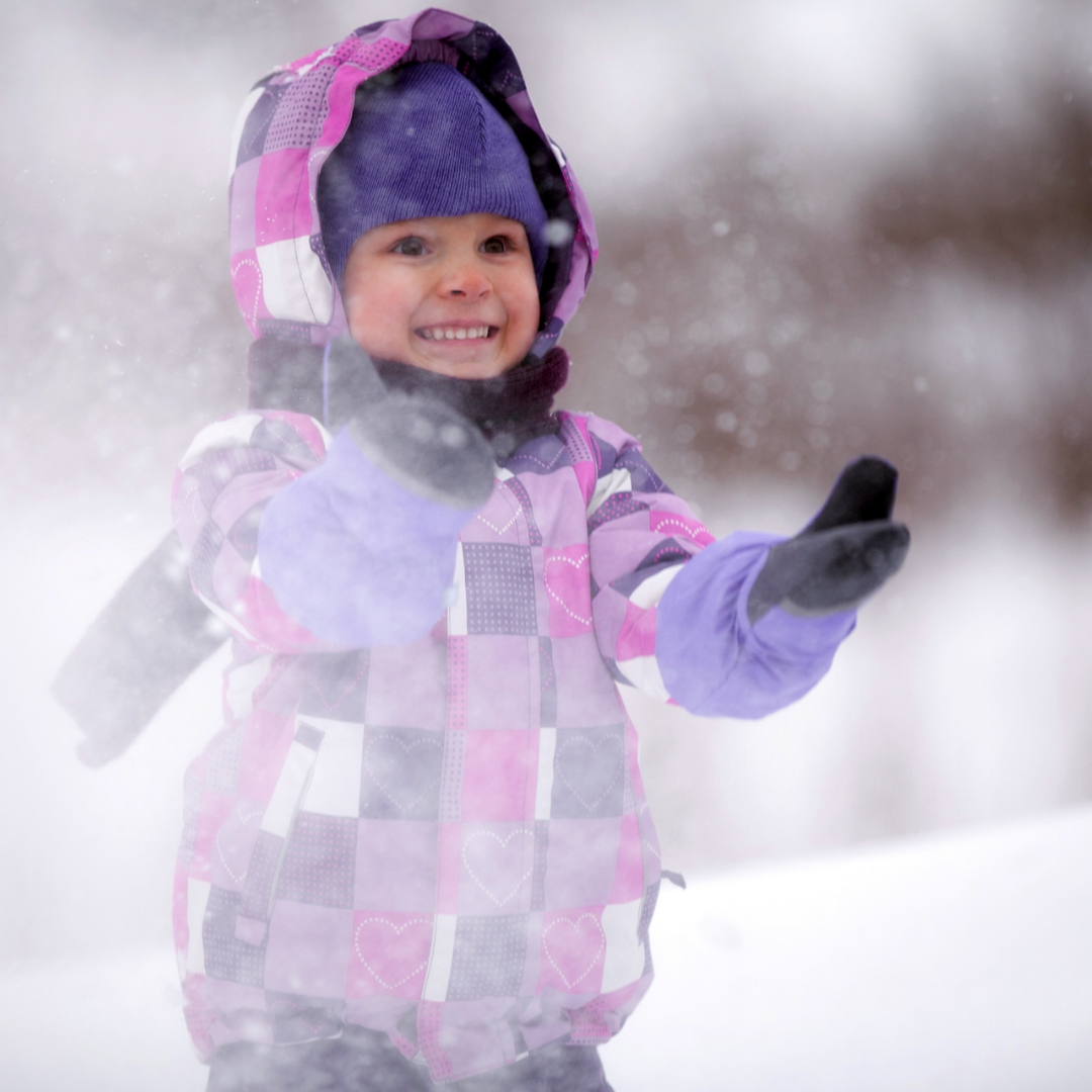 little girl wearing purple mittens in snowstorm