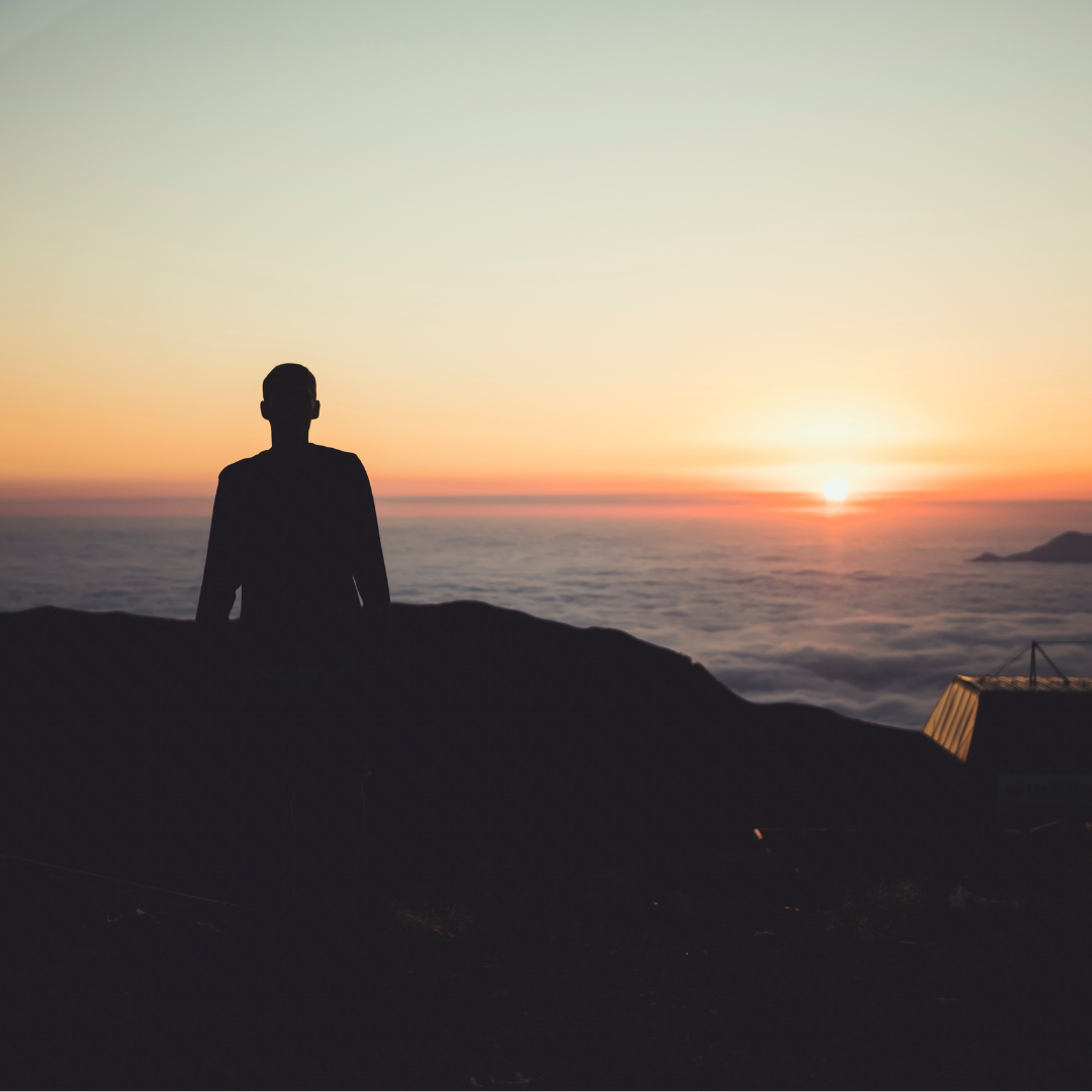 silhouette of man standing on top of a mountain