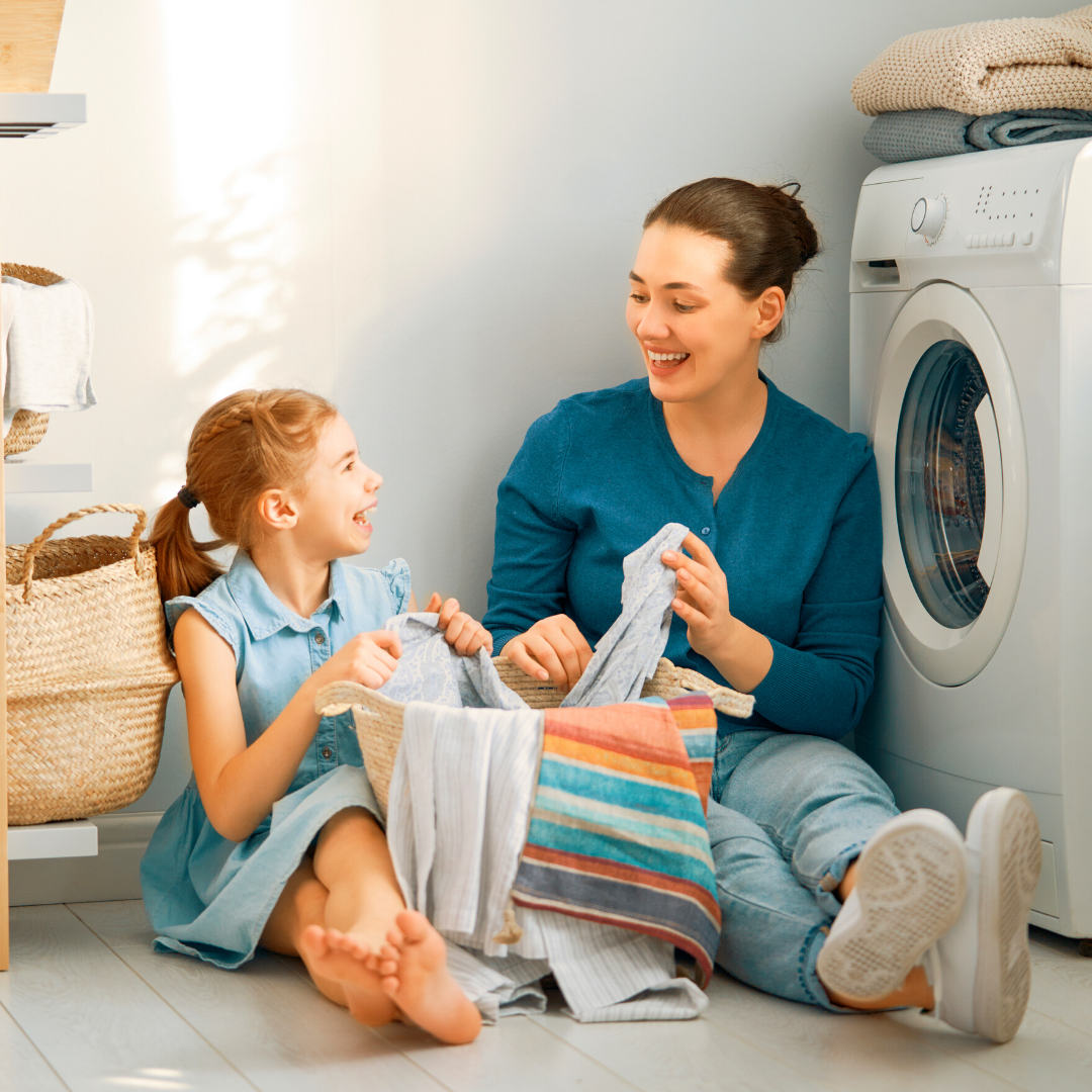 little girl folding laundry with mom