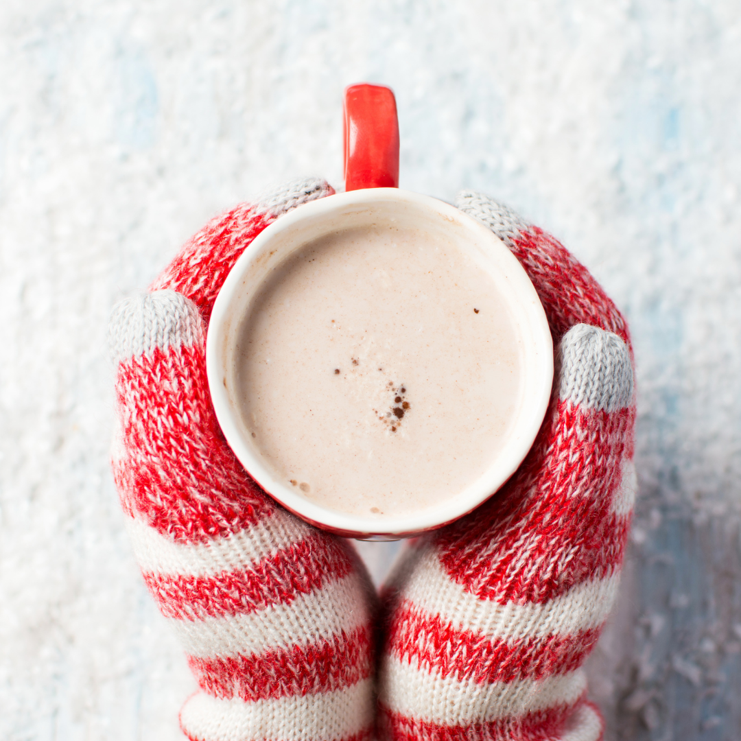 red and white mittened hands holding cup of cocoa