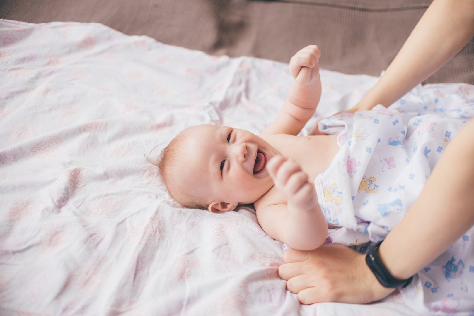 baby smiling at person standing above him