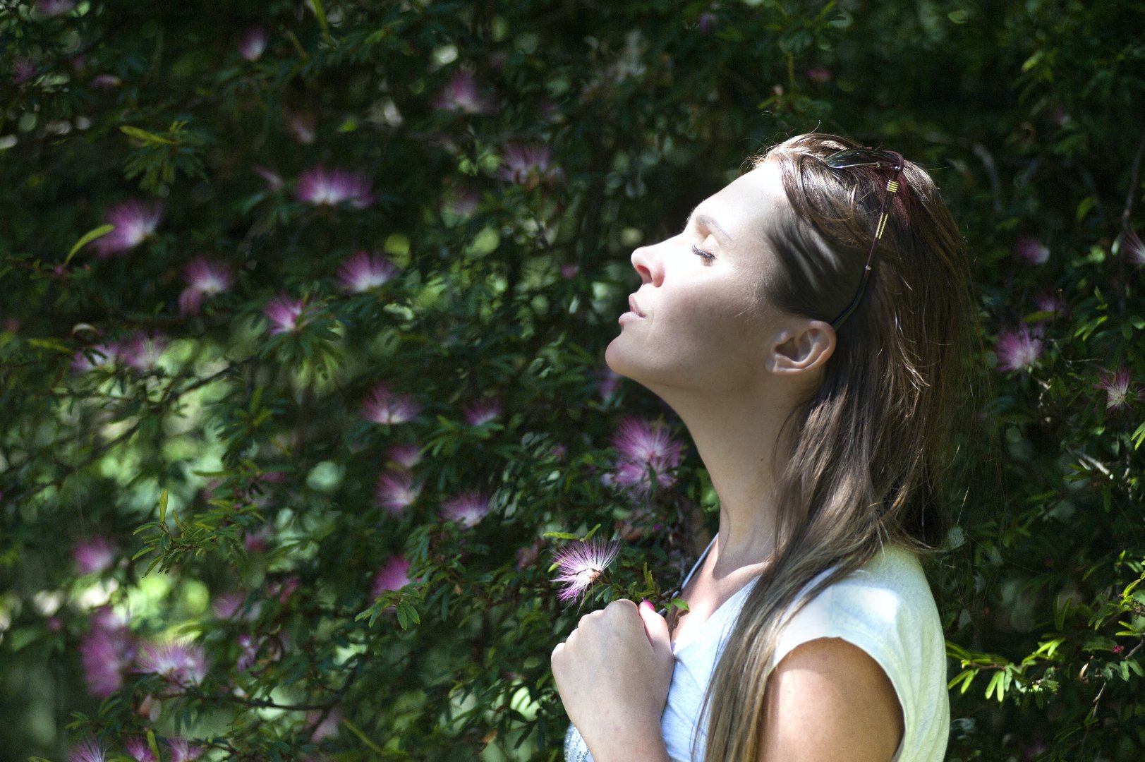 woman standing with eyes closed in front of tree with purple flowers