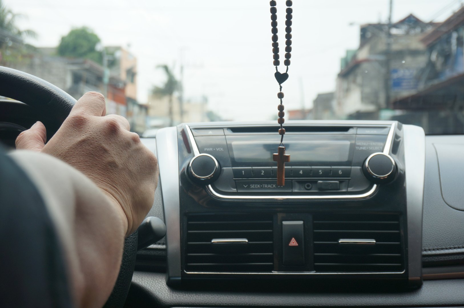 dashboard view of car with Rosary handing from mirror