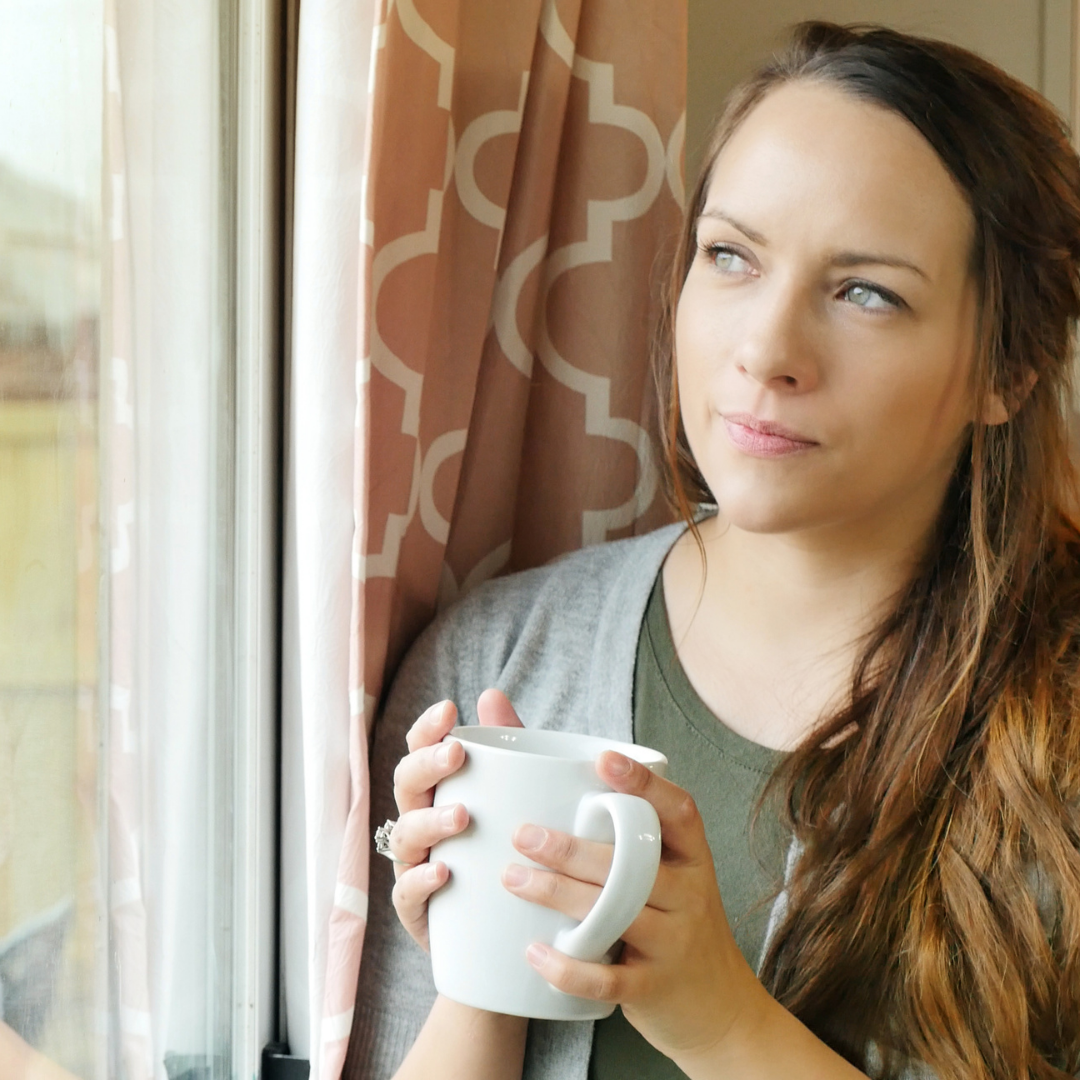 woman holding coffee cup and looking out the window