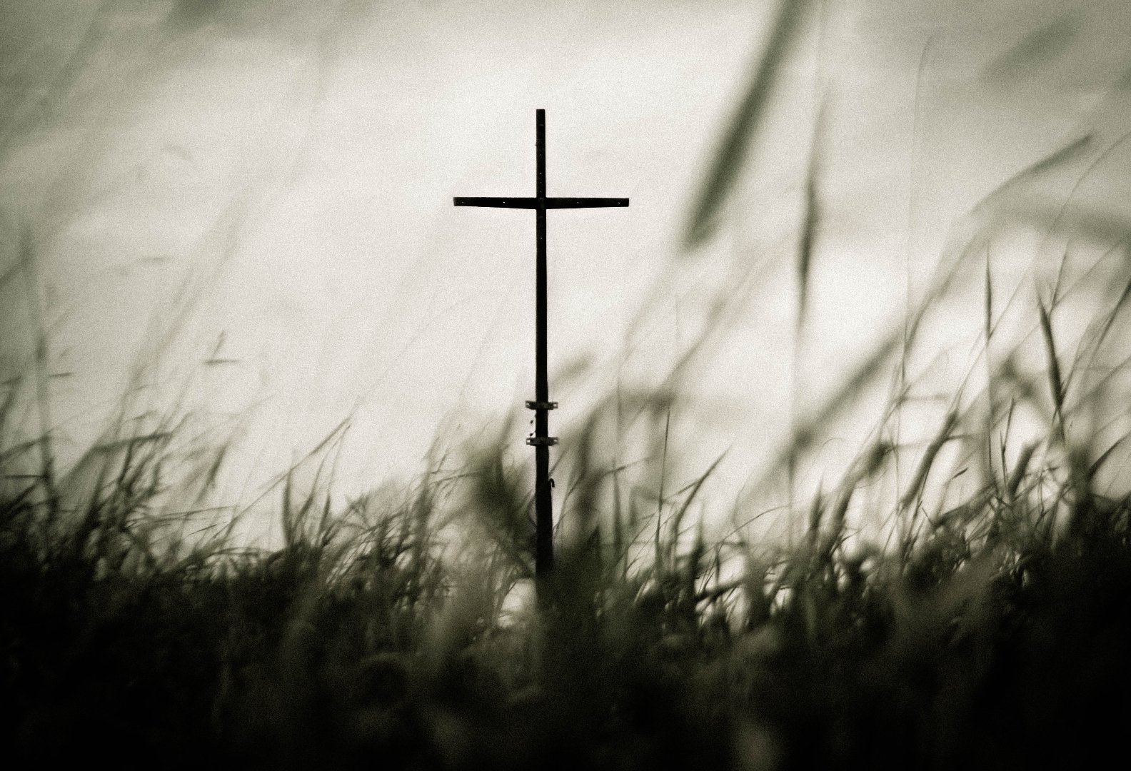 metal cross viewed from below with grass in the foreground