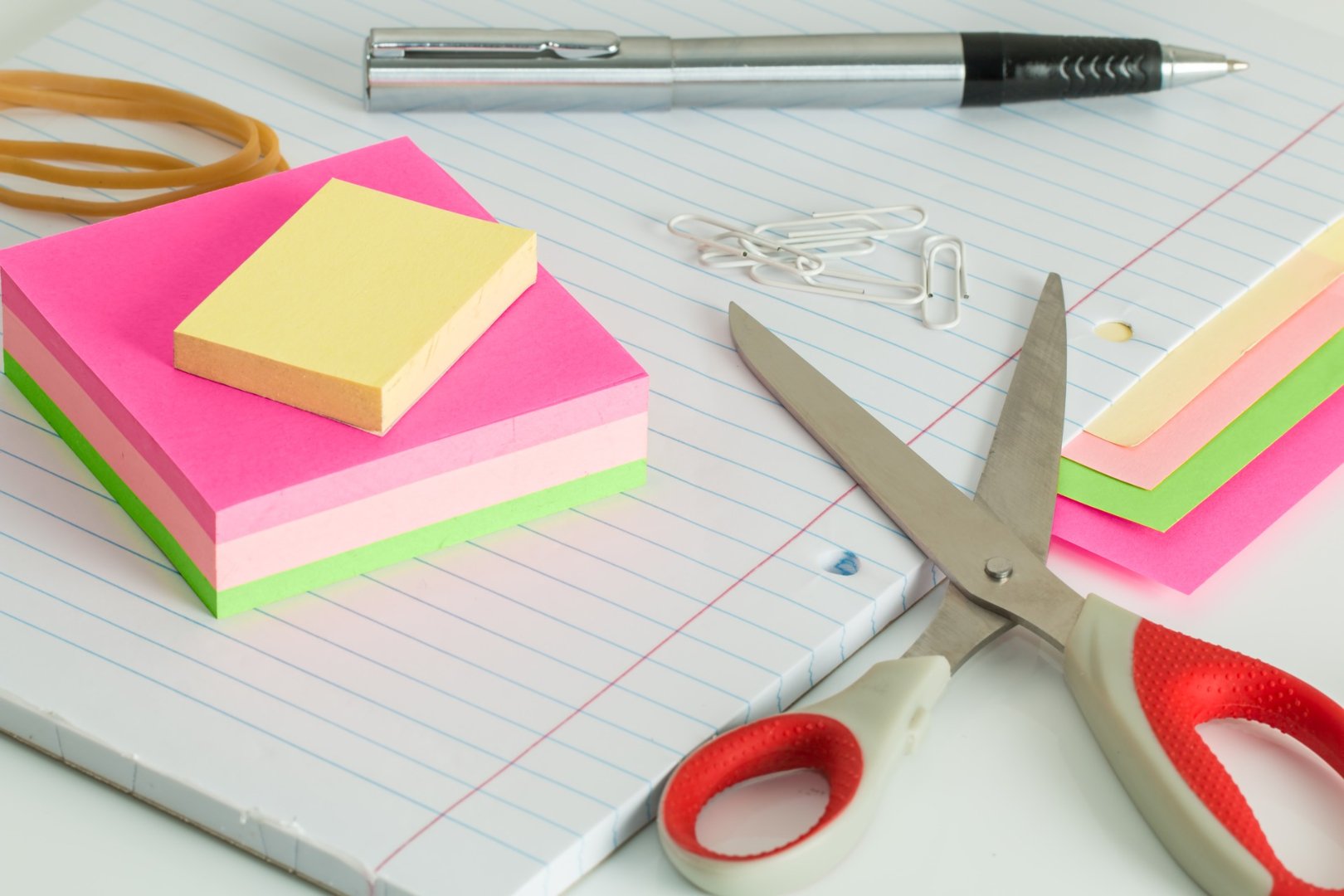 post-its, loose leaf, paper clips and scissors on desk
