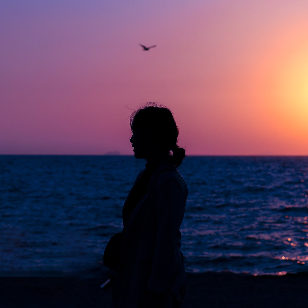 woman silhouetted against ocean sunset