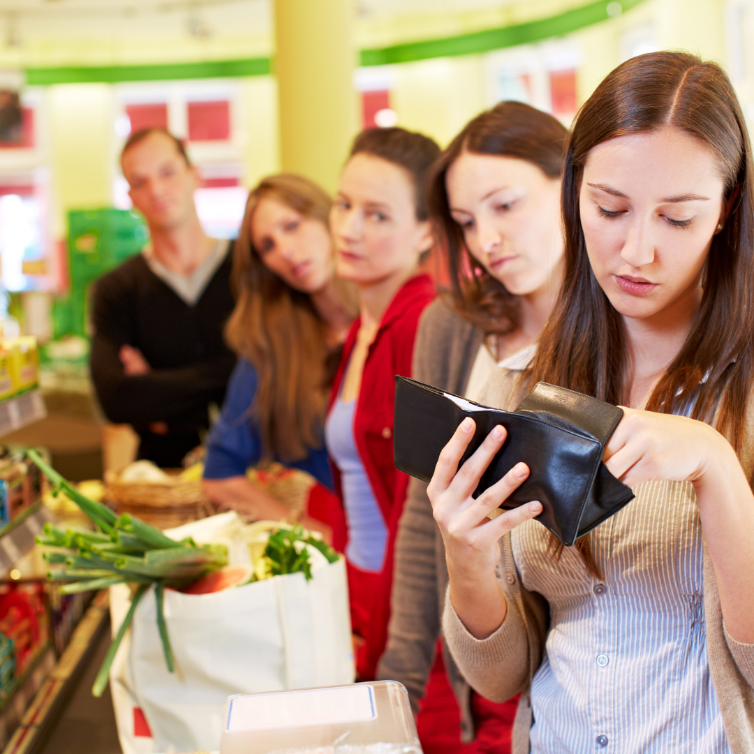 people standing impatiently in line behind woman looking through wallet