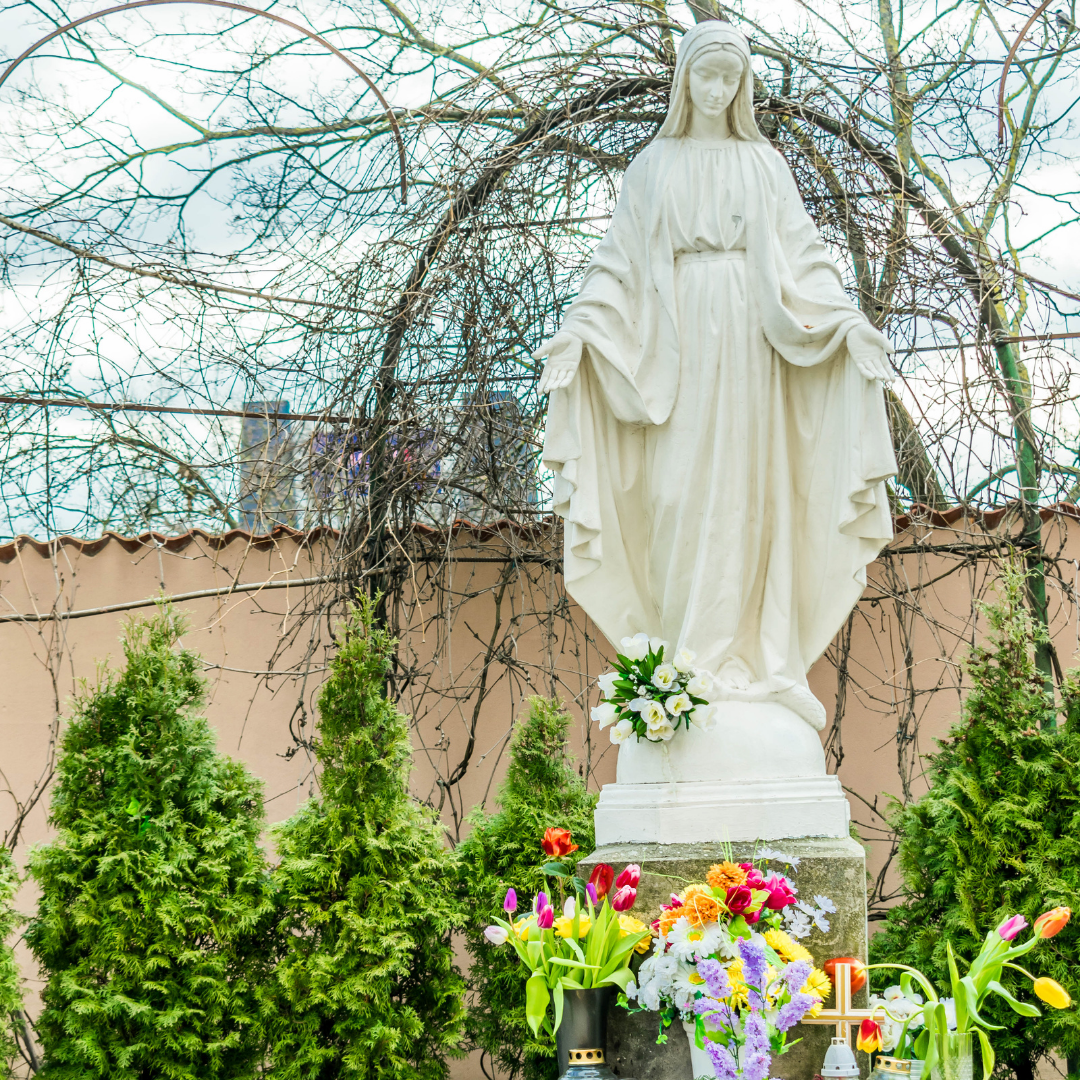 outdoor statue of Mary in garden with flowers at her feet