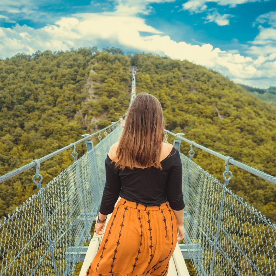 woman preparing to cross bridge over a mountain pass