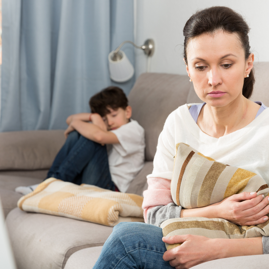 sad mom sitting with her back to sad child