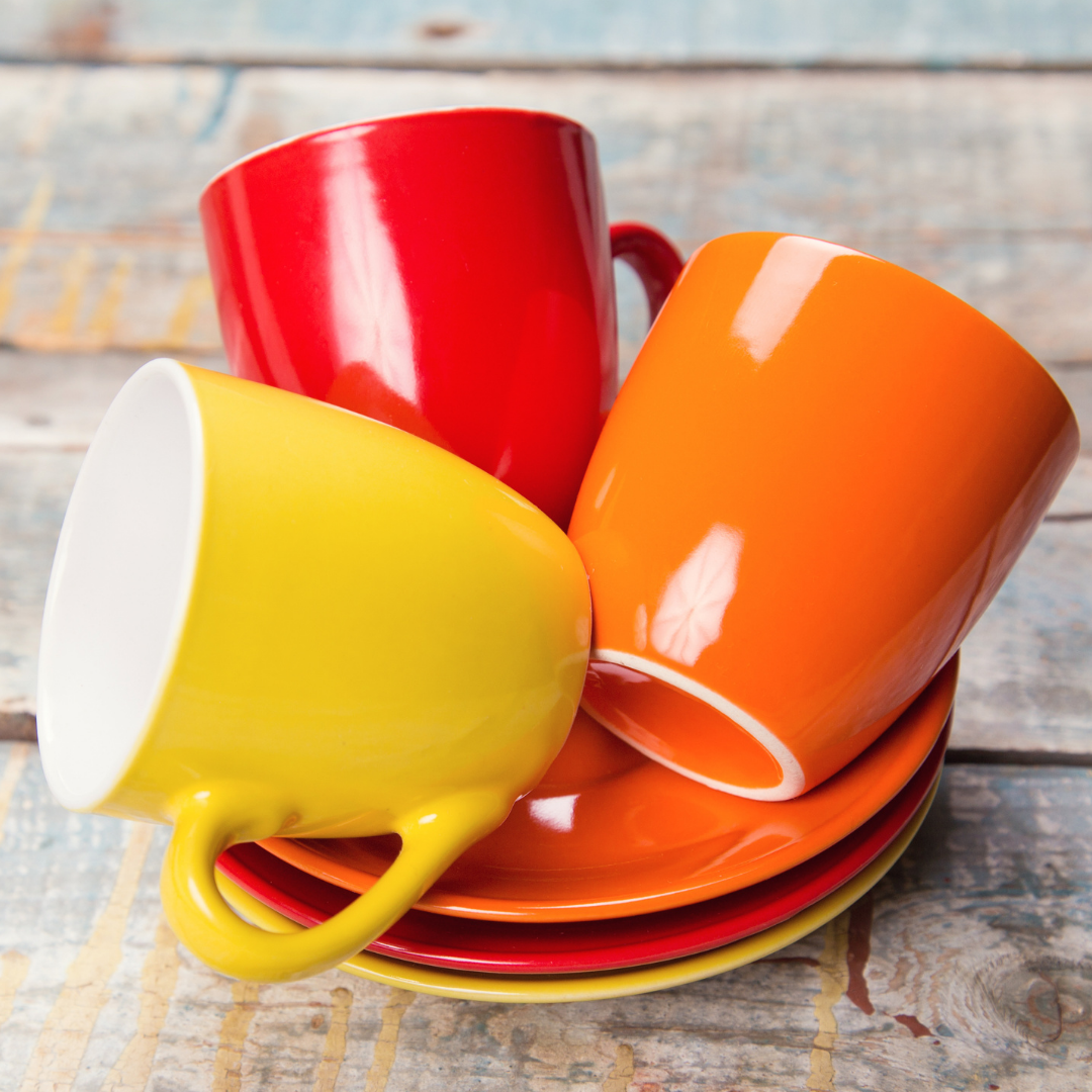 3 bright-colored cups and saucers, empty, cups tipped on their sides
