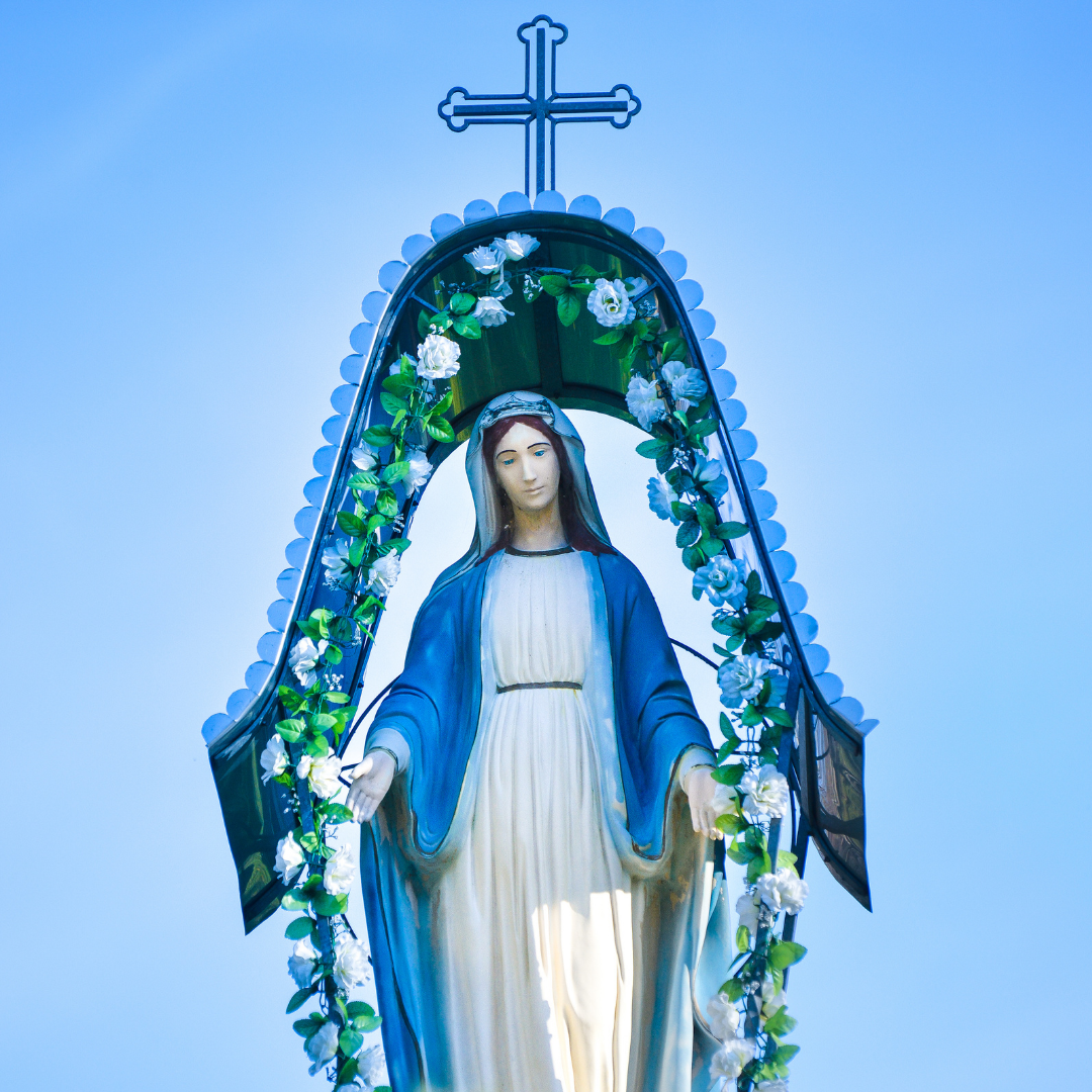 statue of Mary with flowers growing along a border