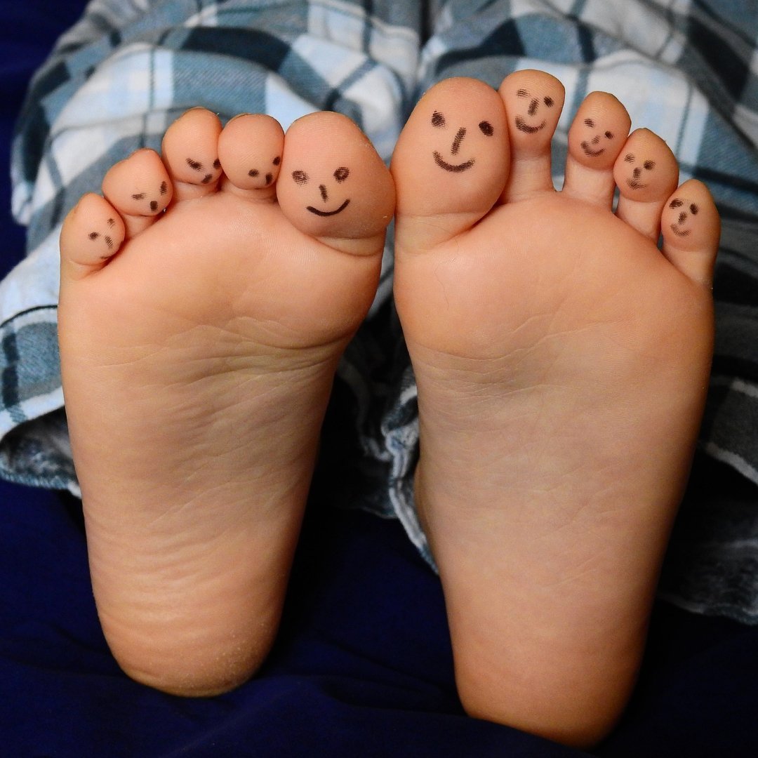 small child's feet with smiley faces drawn on the toes