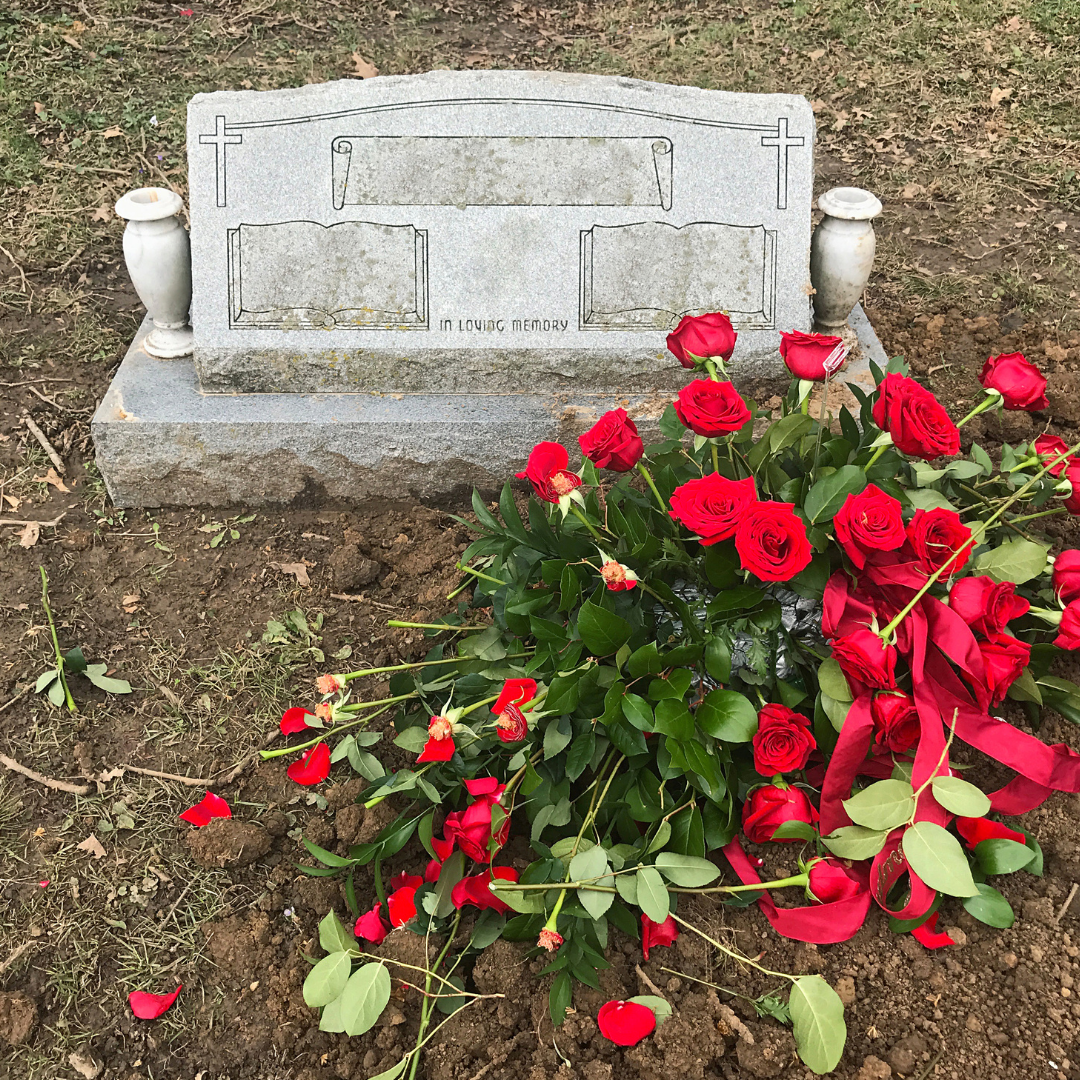 unmarked gravestone with fresh red roses