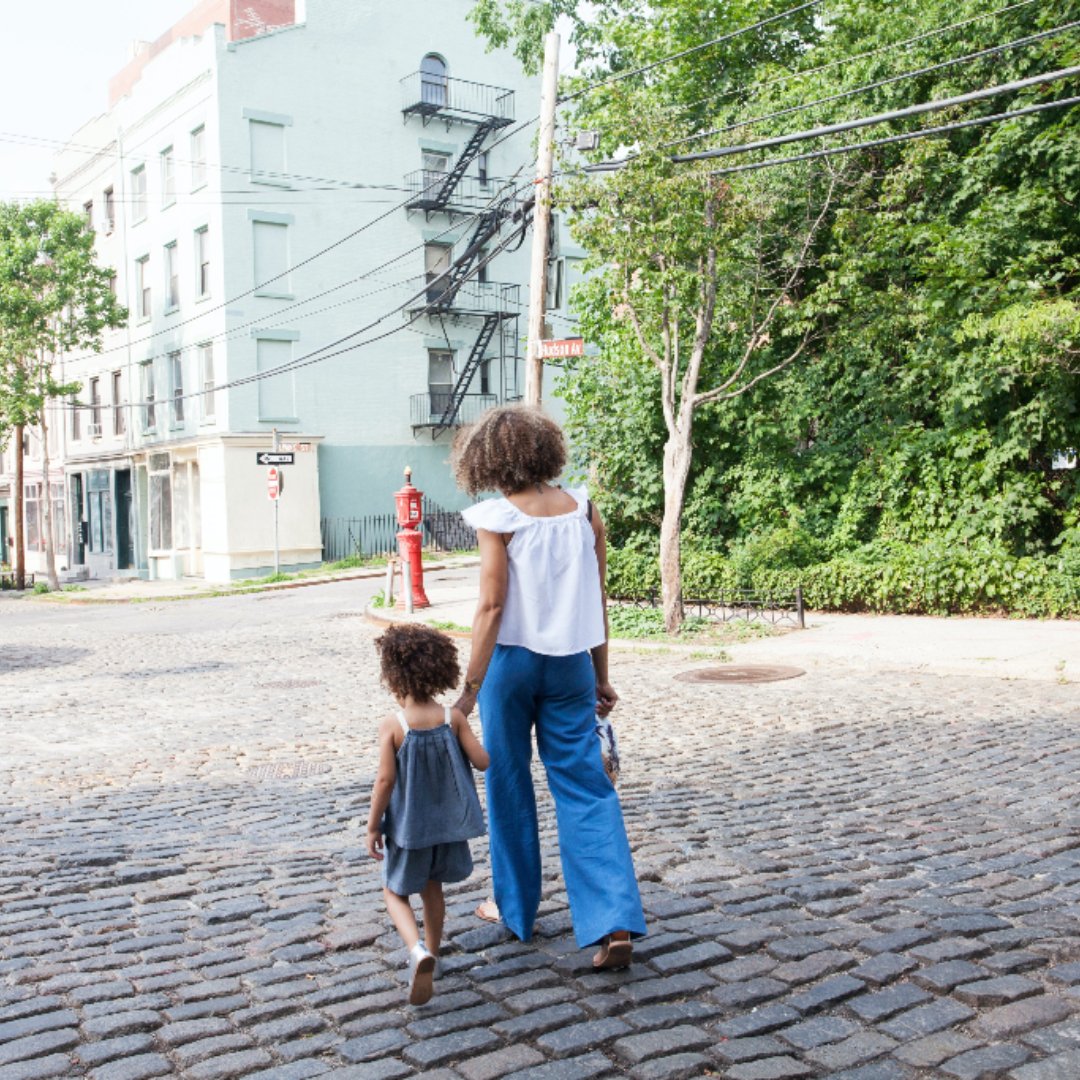 Mother and daughter walking along cobblestoned street
