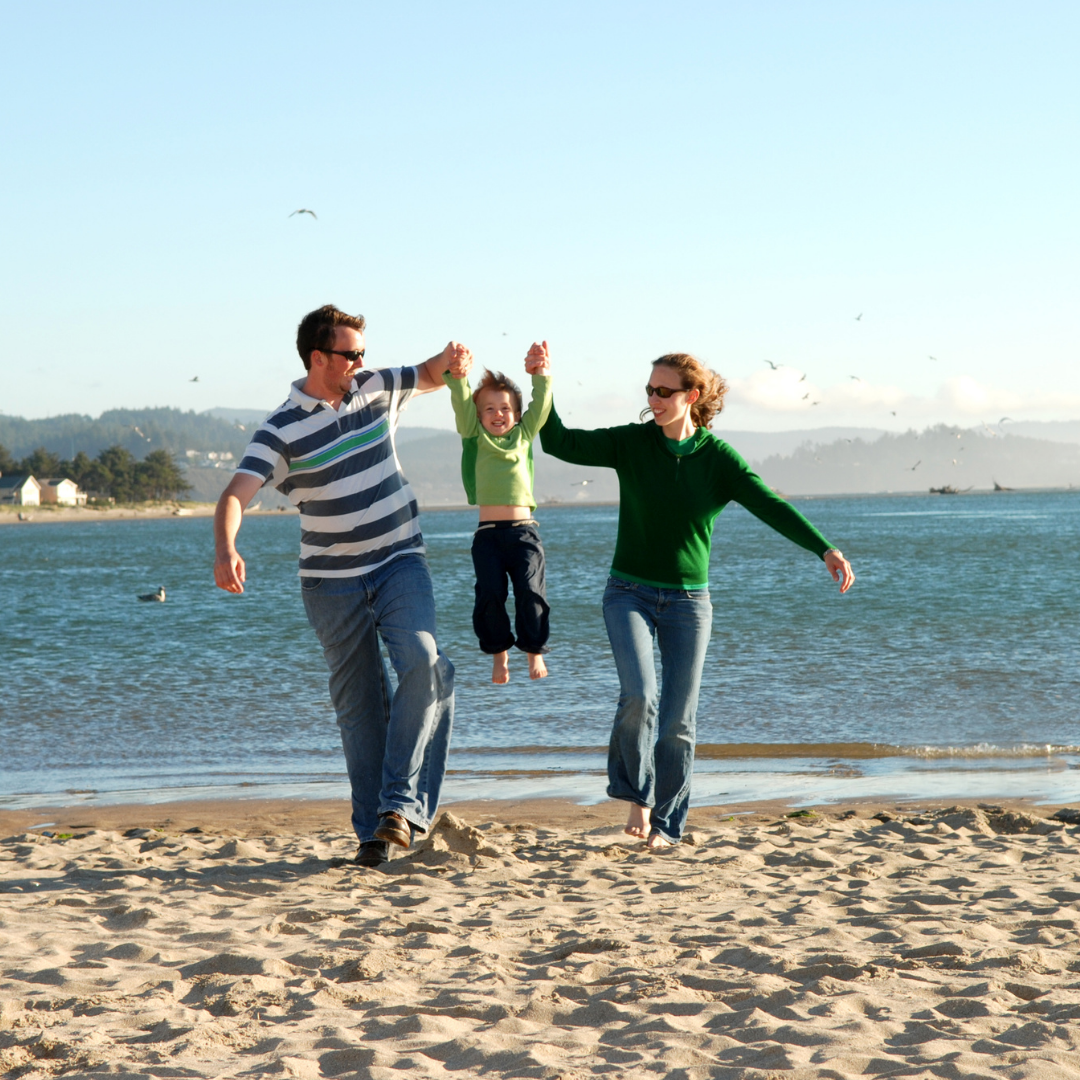 parents lifting small child on a beach