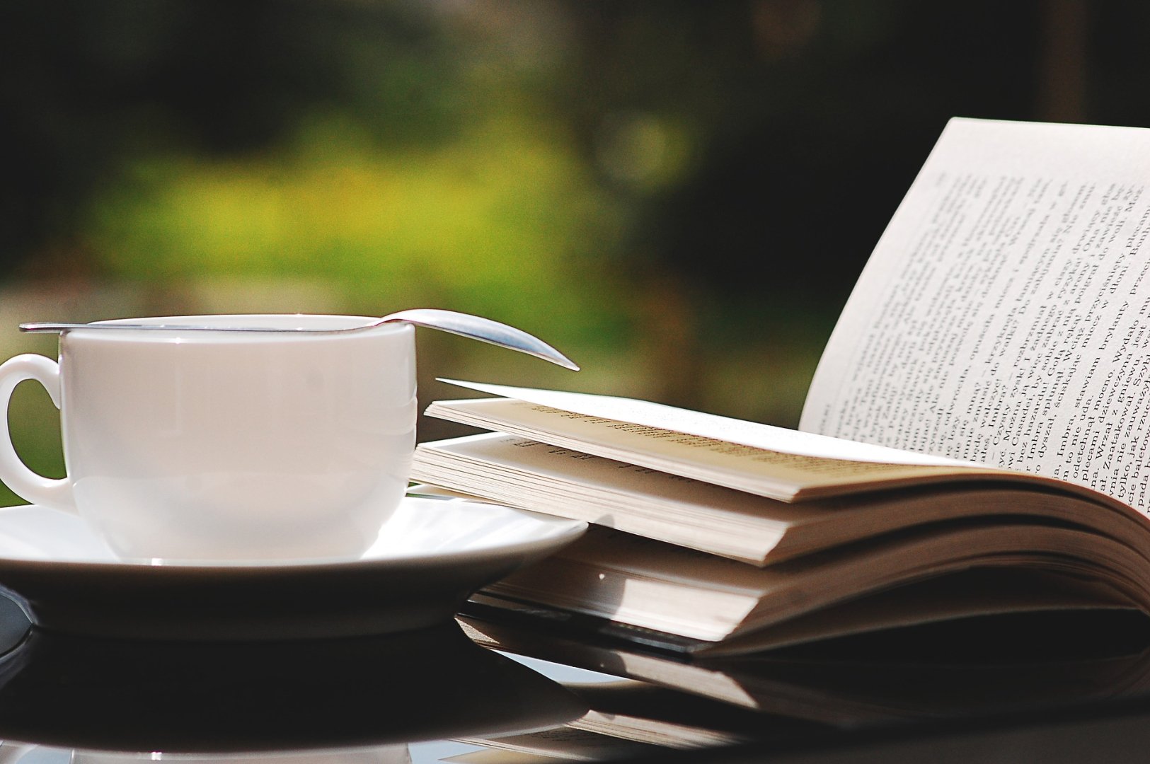teacup with spoon on top next to open book