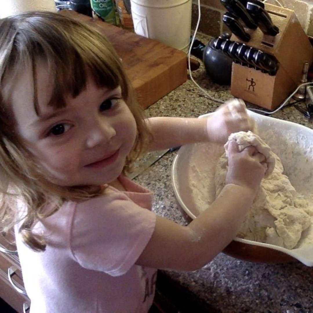 little girl kneading bread dough