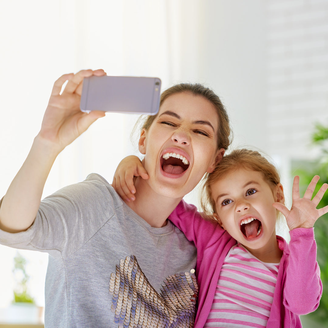 mom and daughter taking selfie and making silly faces