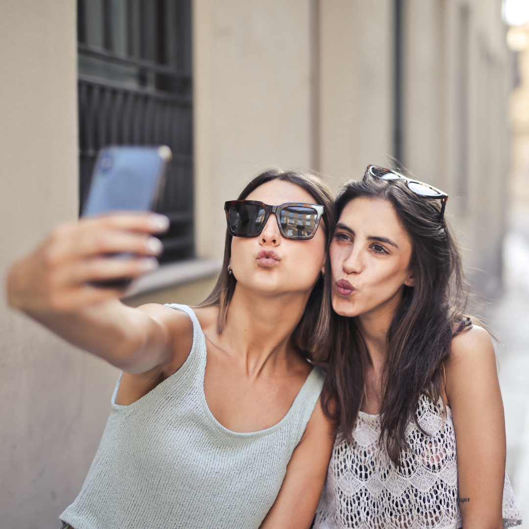 2 young women taking selfies with puckered lips