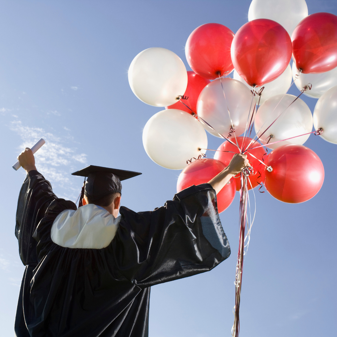 graduate holding diploma and a bunch of red and white balloons