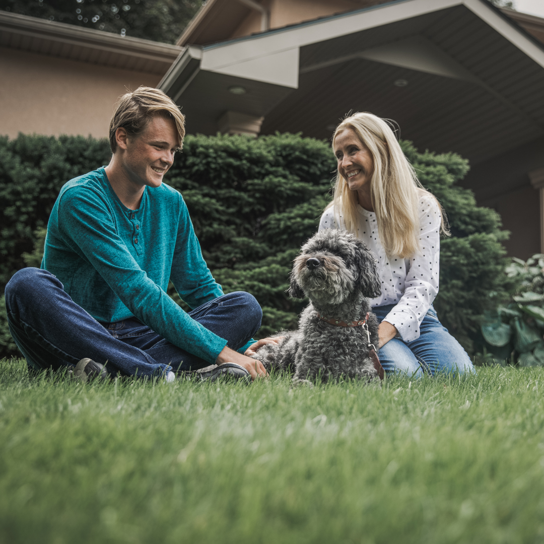 mom with teenage son and dog in front of house