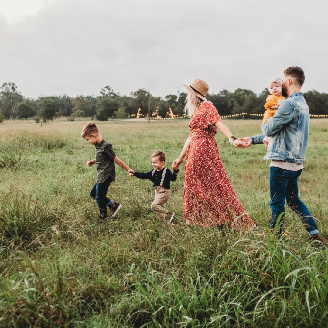 little boy leading family through a field