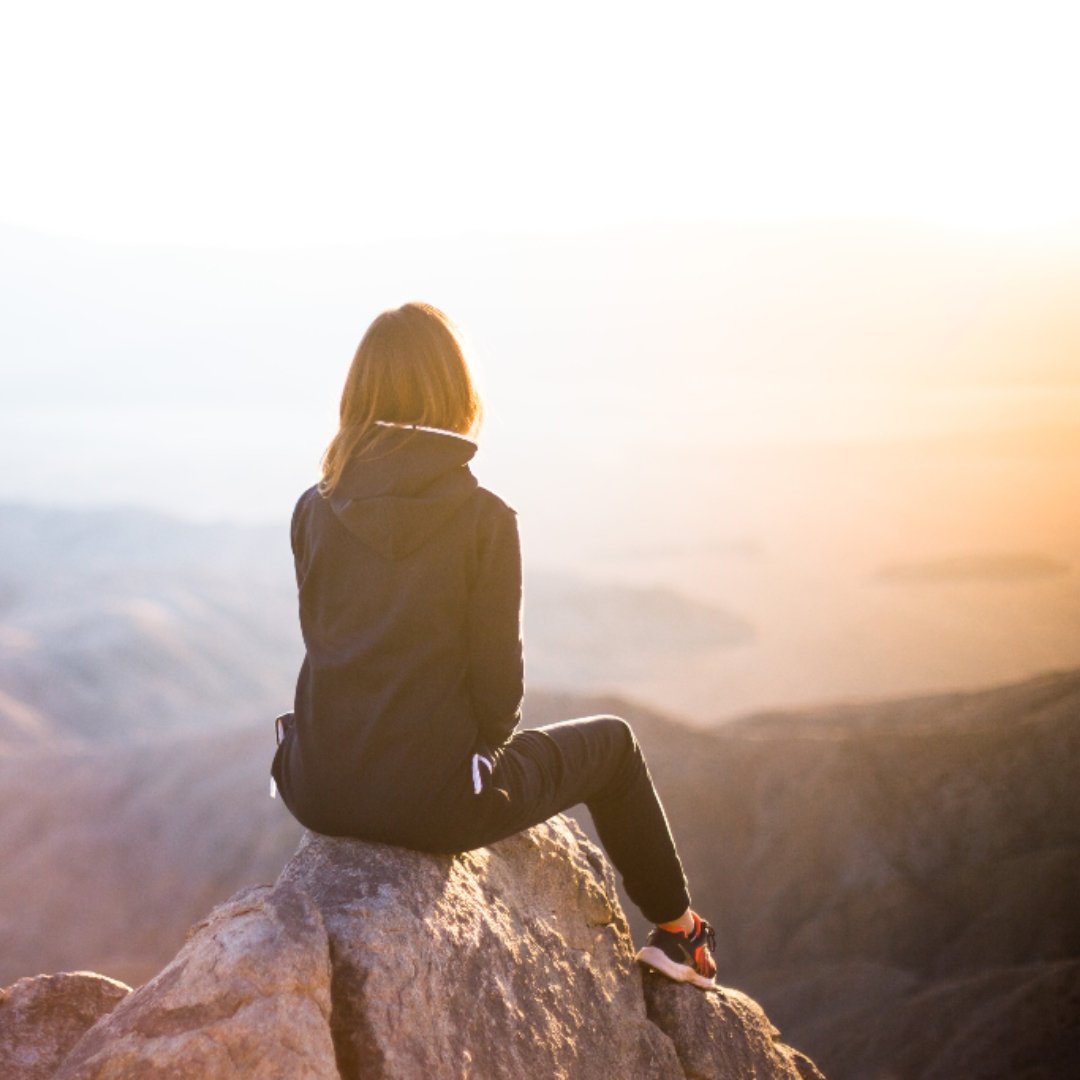 woman sitting on mountaintop