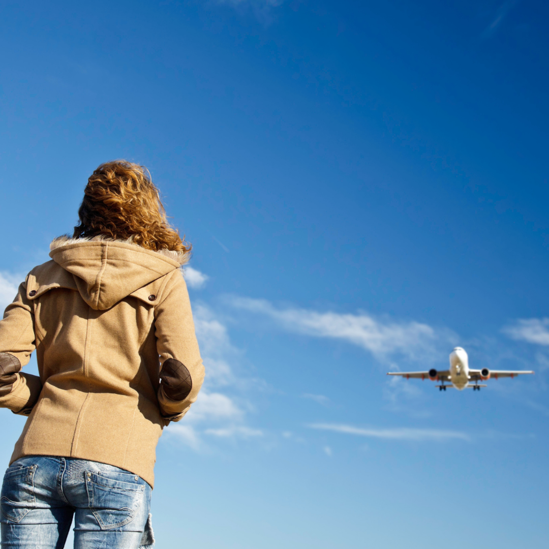 woman looking at airplane flying overhead