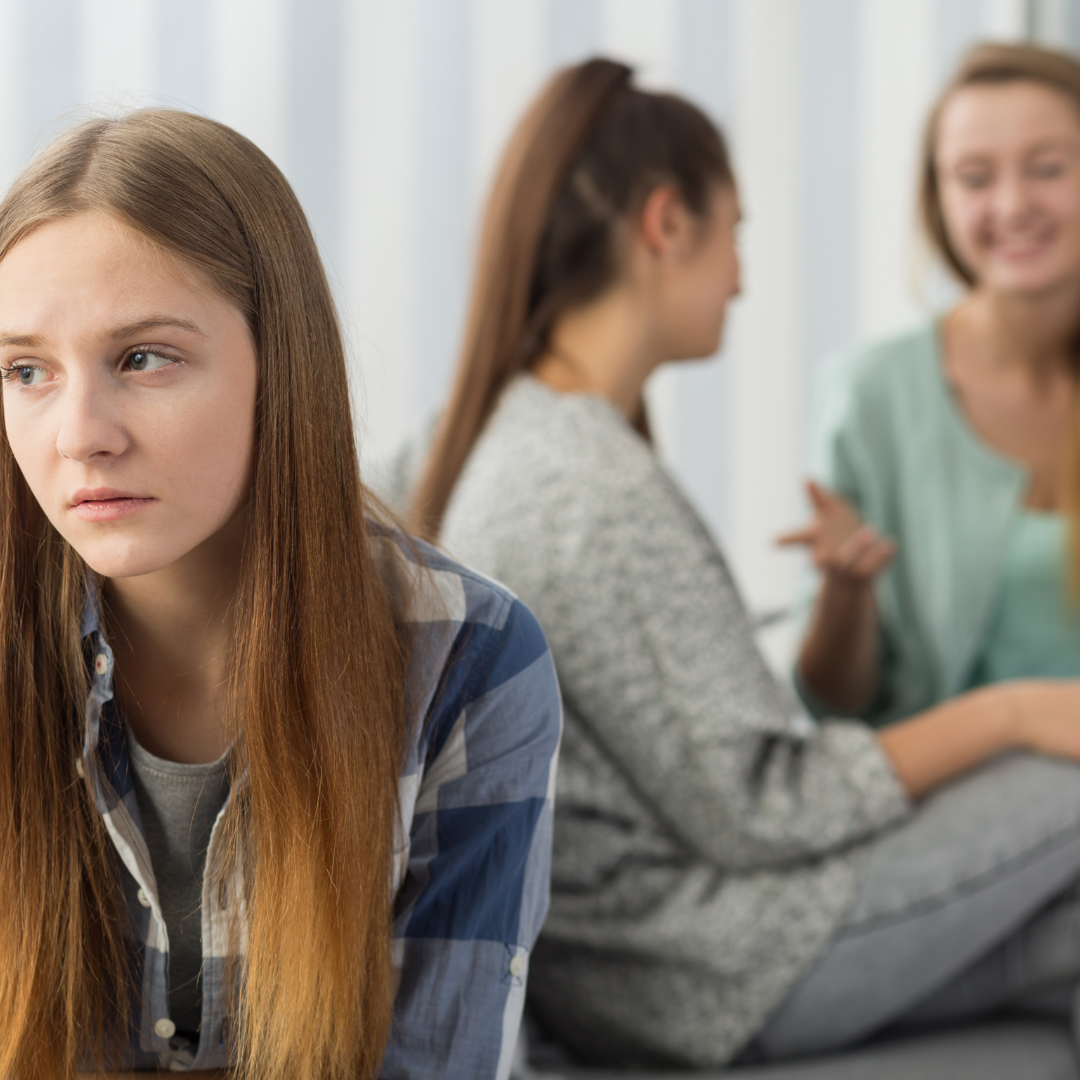 lonely young woman near 2 friends who ignore her