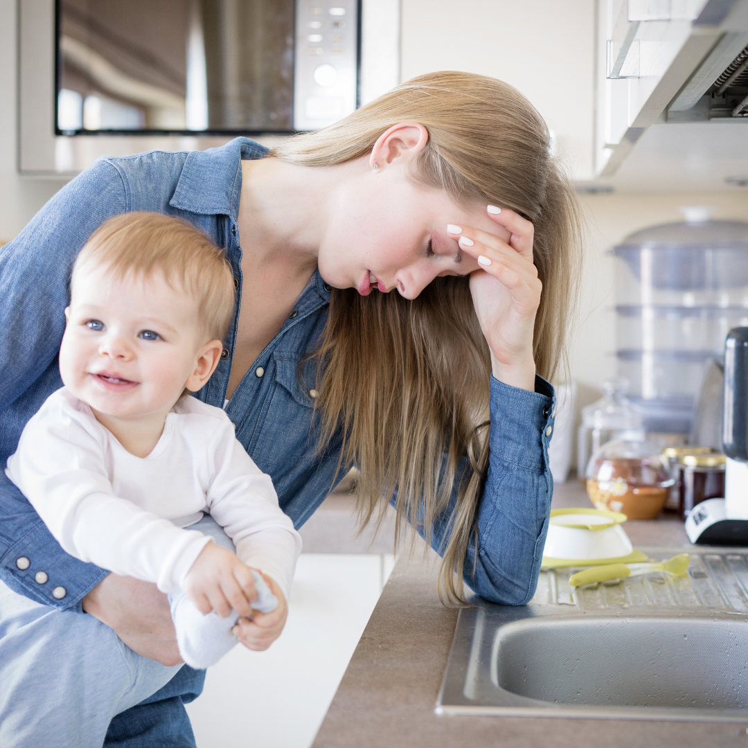 tired mom holding toddler in kitchen