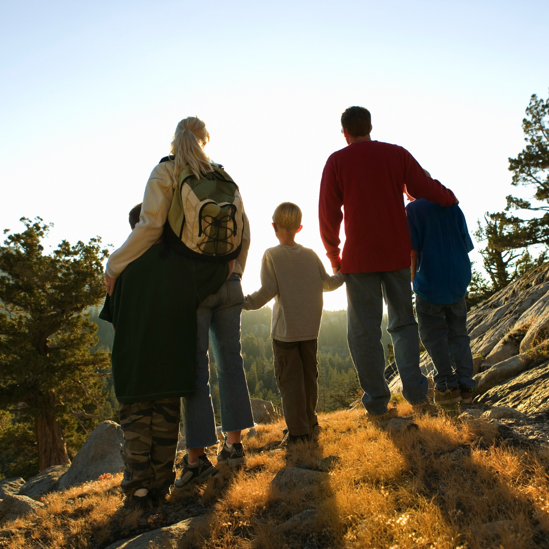 family gazing at sunset from top of a mountain