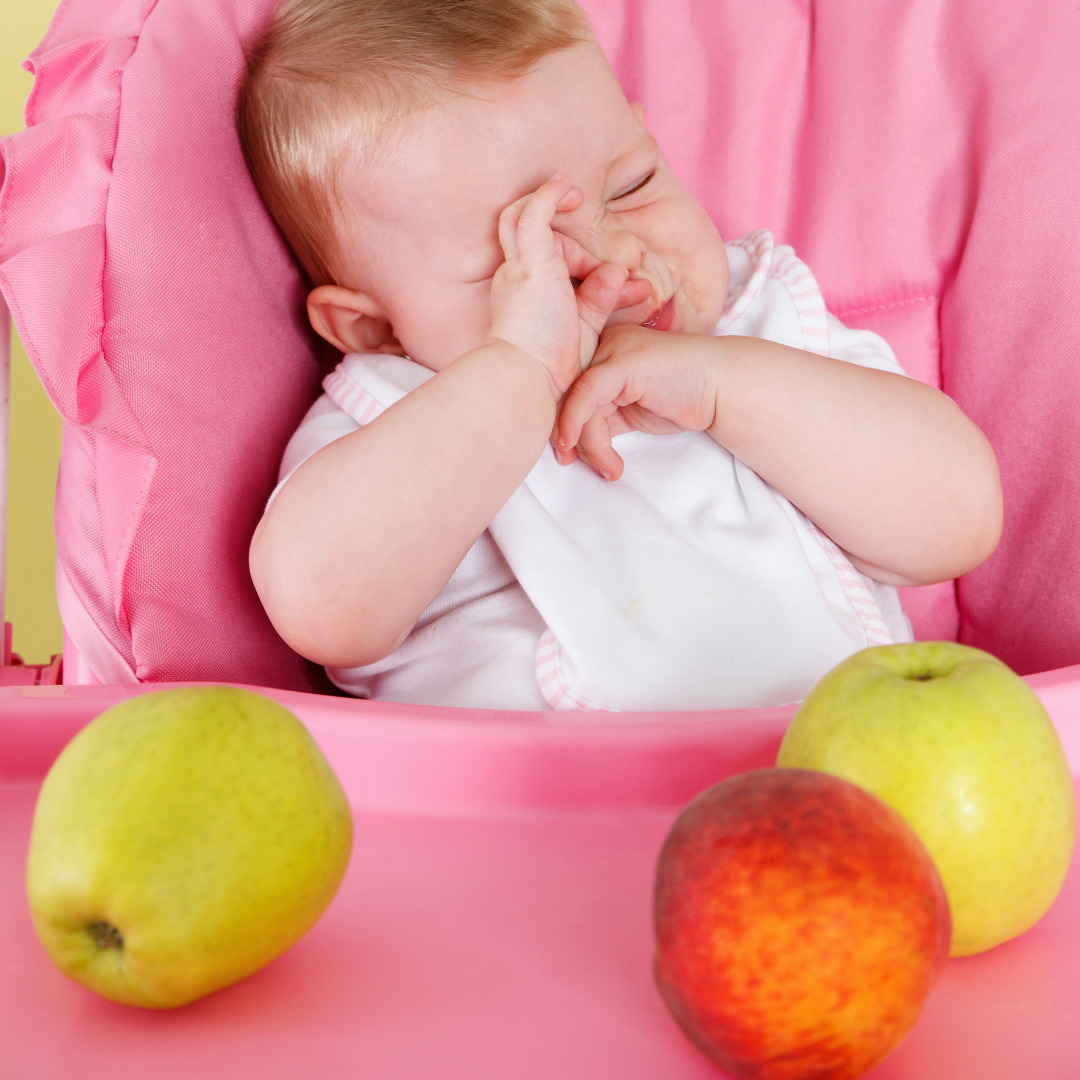 baby in high chair with apples on tray