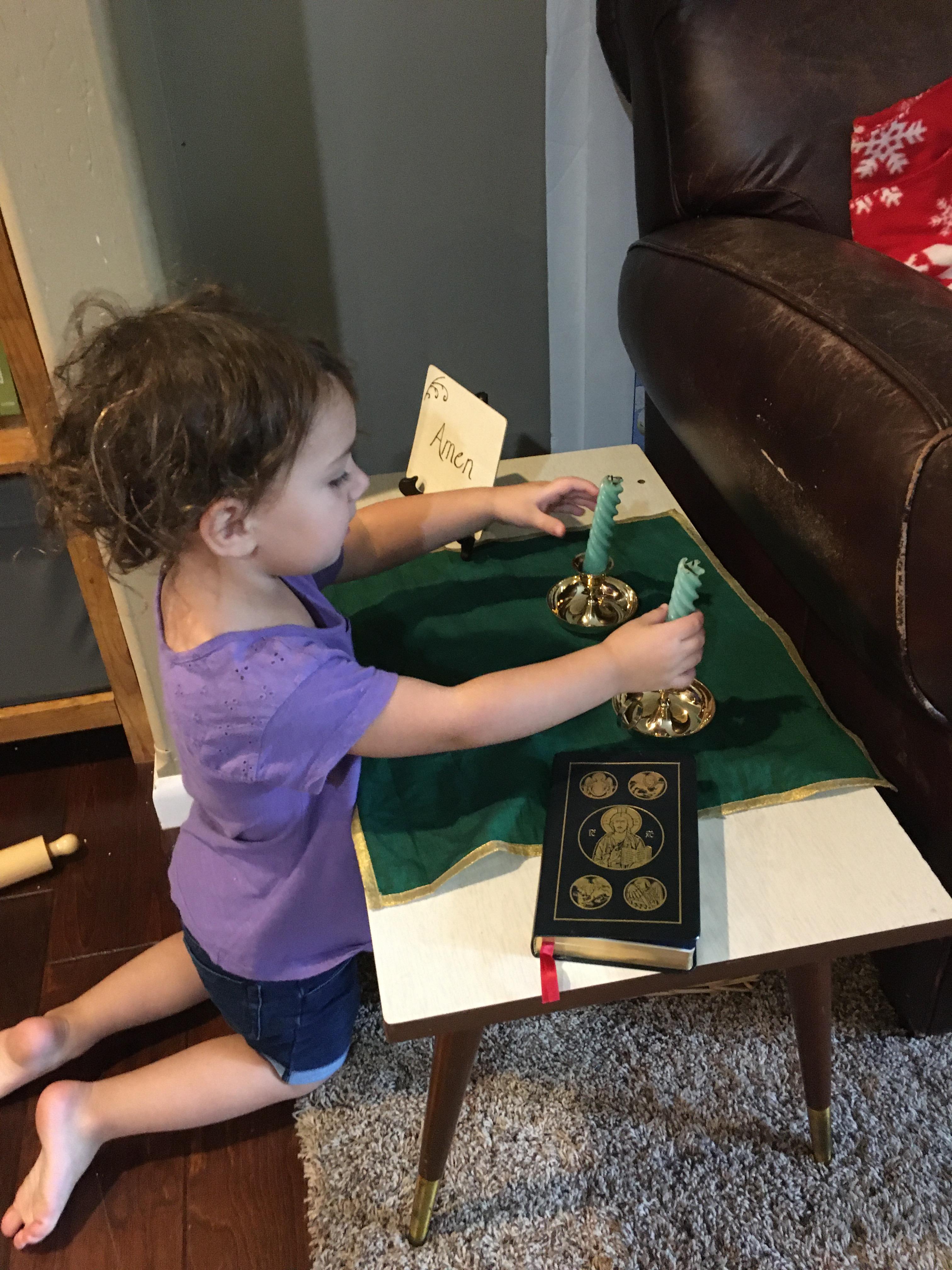 toddler reaching for candles at prayer table