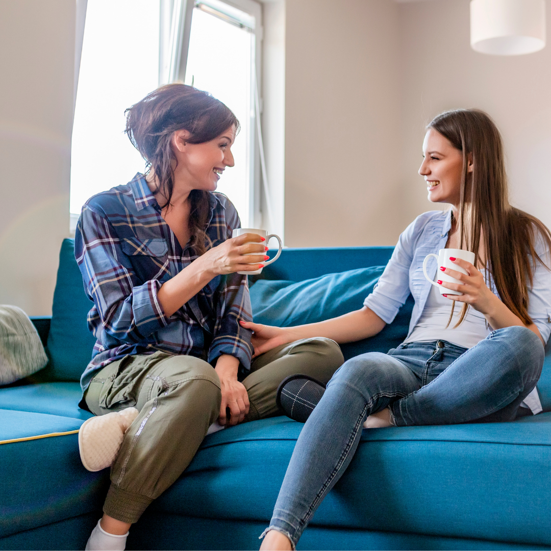 friends sitting on couch, drinking coffee and laughing