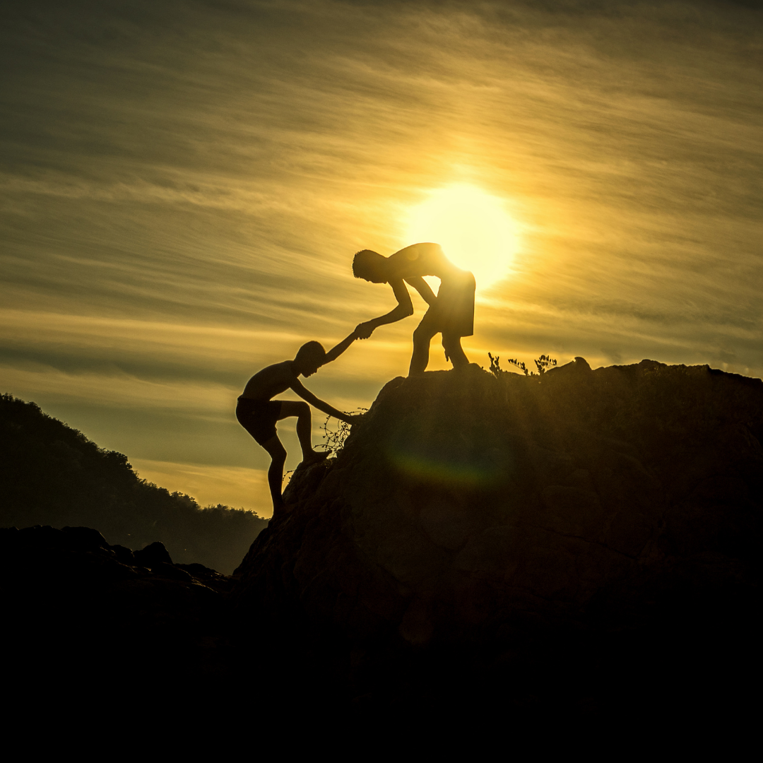 mountain climber helping another summit the mountain