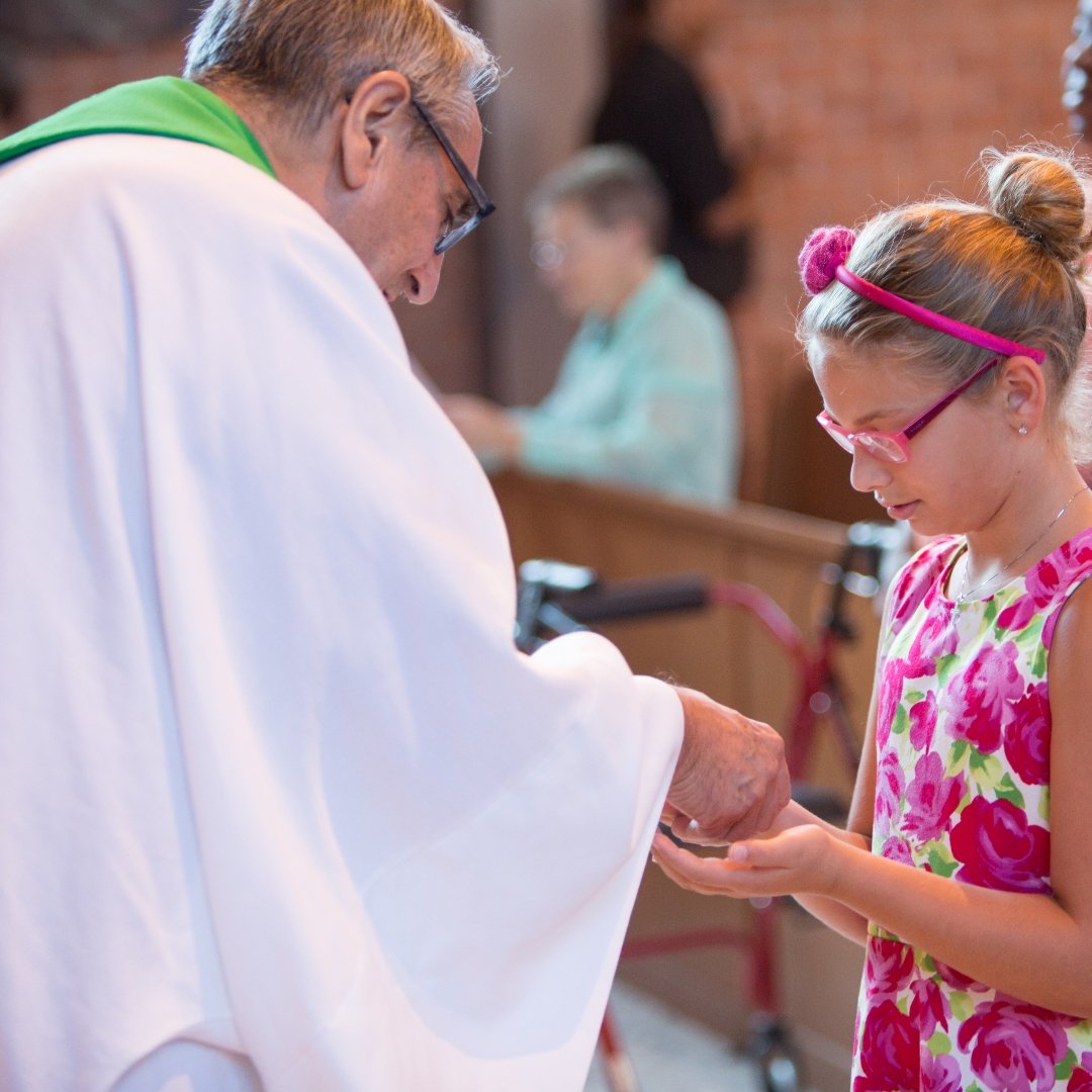 Young girl receiving Communion from priest